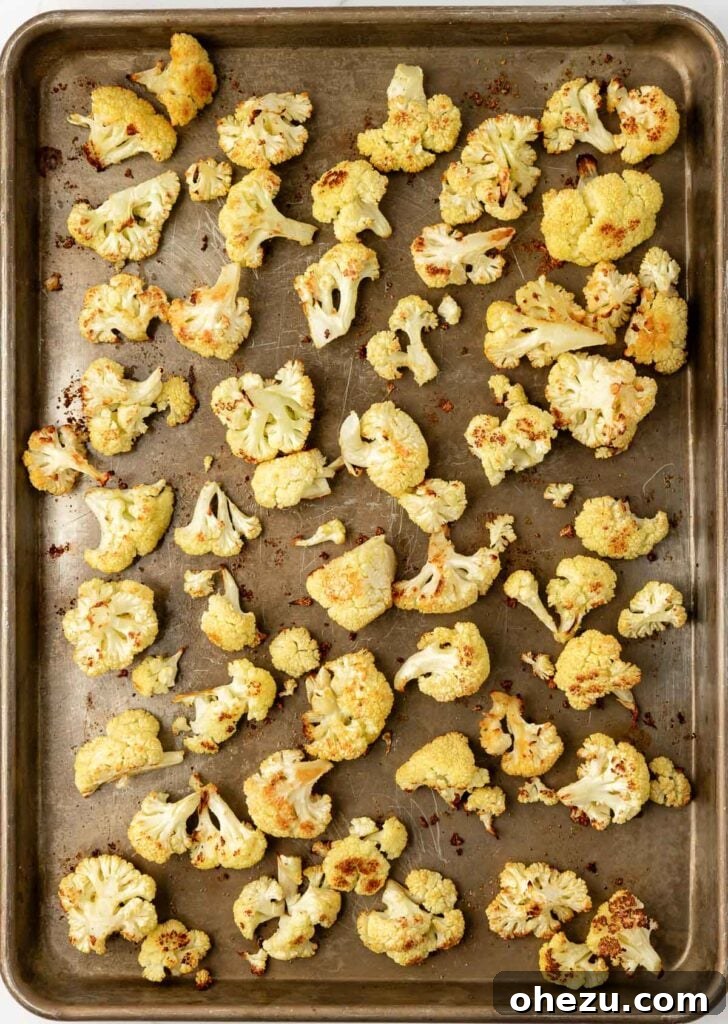 partially roasted cauliflower on a baking sheet, showing some browning