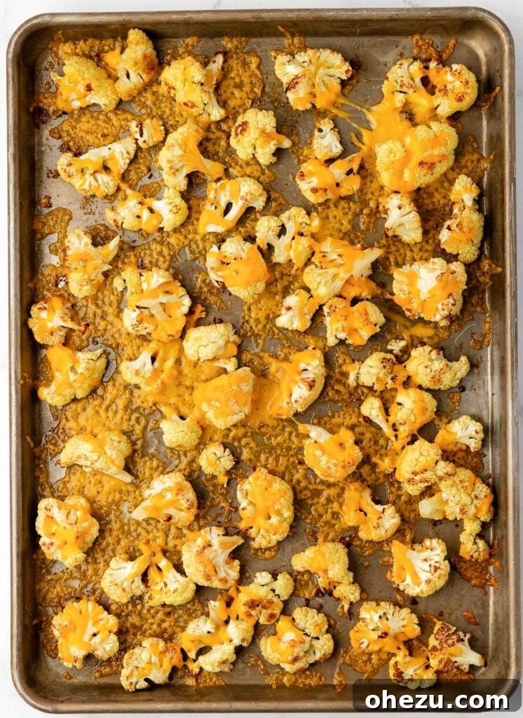 finished cheesy roasted cauliflower with melted, crispy cheese on a baking sheet