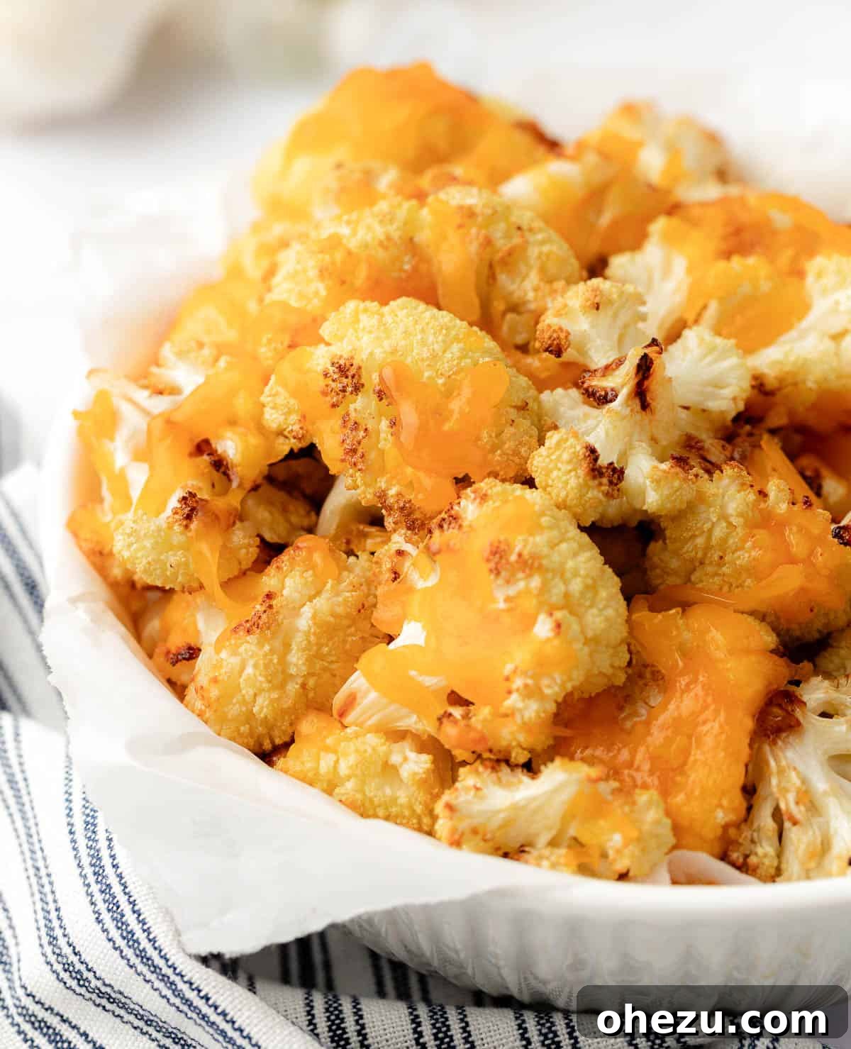 cheesy cauliflower in a serving bowl, perfectly cooked and garnished