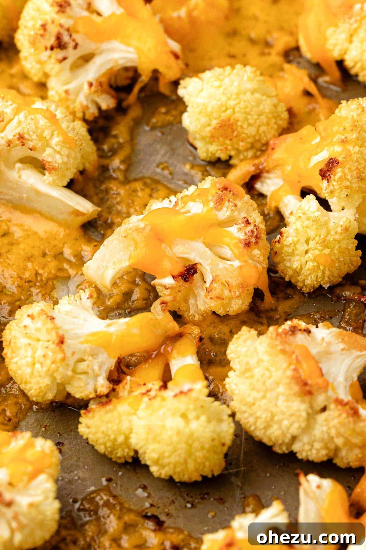 close-up of roasted cauliflower with melted cheese on a baking sheet