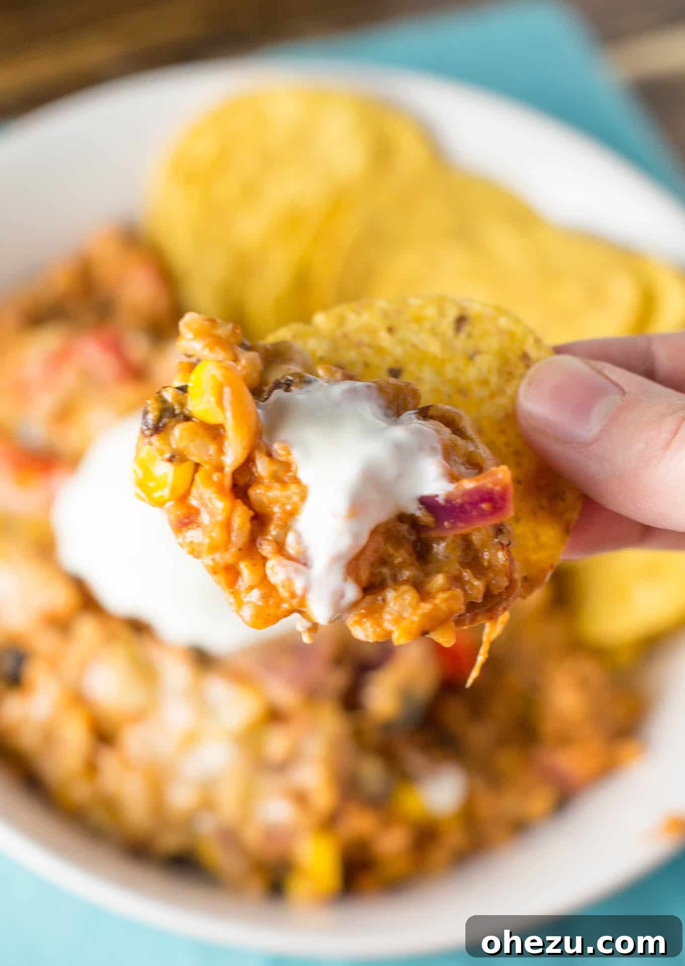 Fiesta Vegetarian Bake 14 A bowl of gluten-free Mexican rice casserole, topped with sour cream, lime, and cilantro, next to a basket of tortilla chips