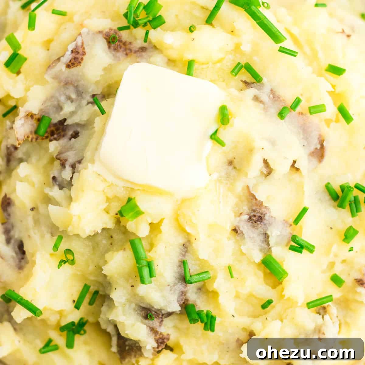 Creamy vegan mashed potatoes topped with melted vegan butter and fresh chives, ready to be served at a holiday feast.