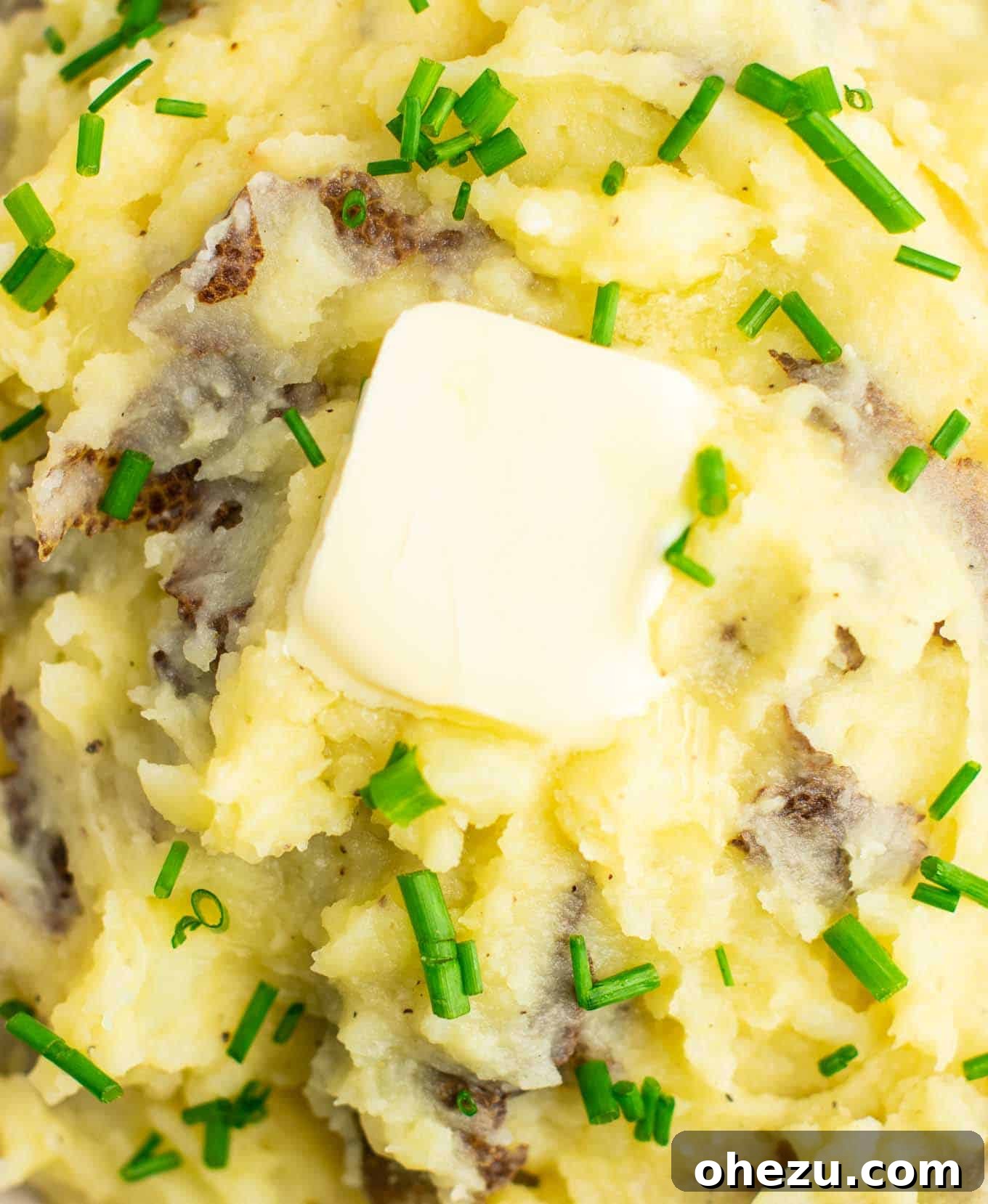 Close-up shot of fluffy mashed potatoes with a pat of vegan butter melting on top, highlighting its creamy texture.