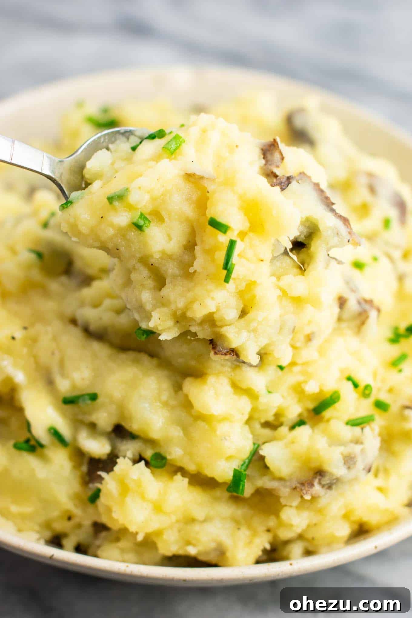 Close-up of perfectly boiled potatoes in a pot, ready for mashing, with steam rising.