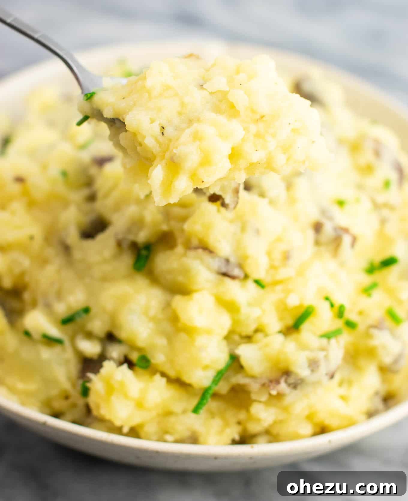 A scoop of rich, creamy vegan mashed potatoes being served from a bowl, highlighting its perfect texture.