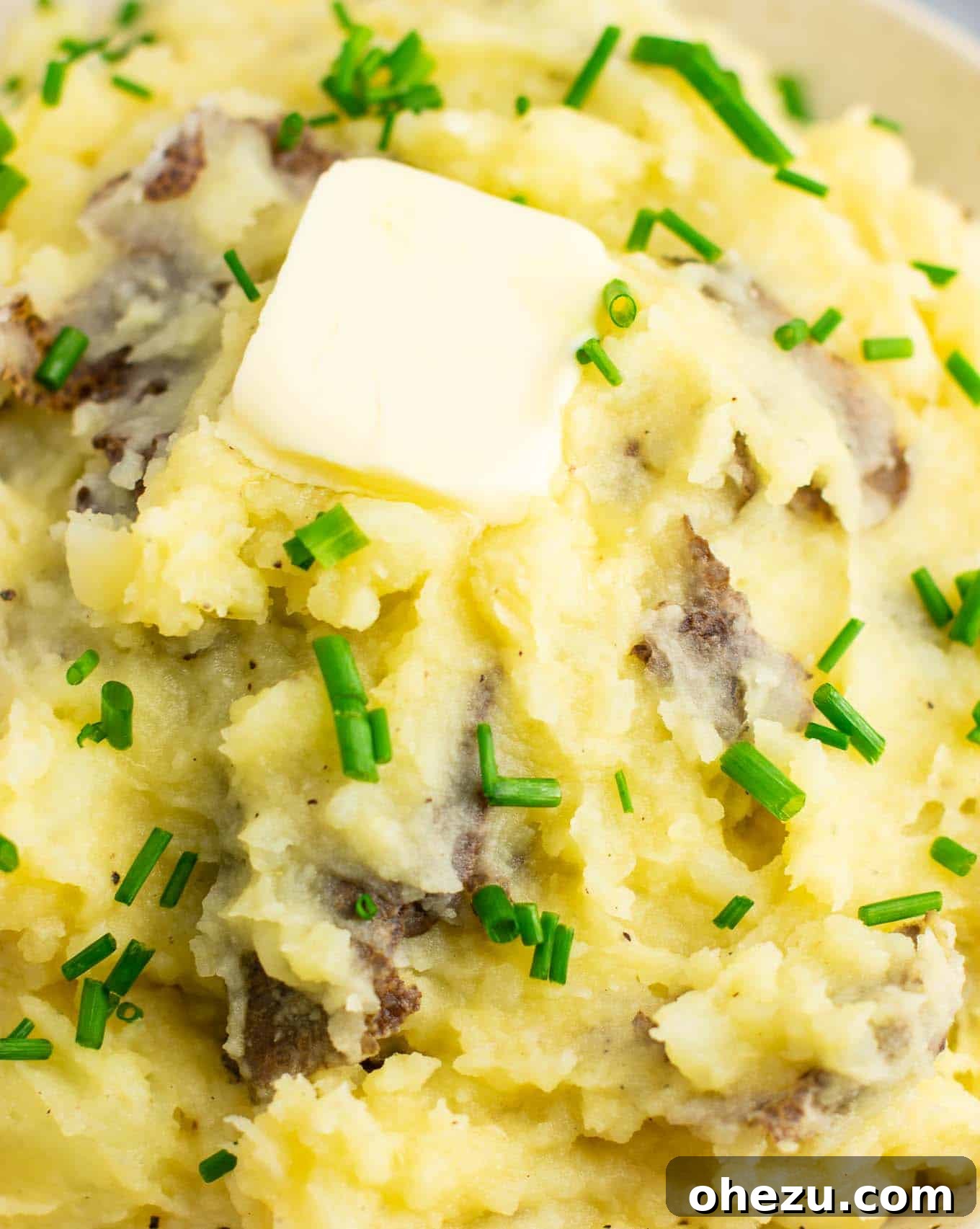 A beautiful close-up of vegan mashed potatoes in a bowl, with a rich pat of vegan butter melting and a sprinkle of chives, ready for a special meal.