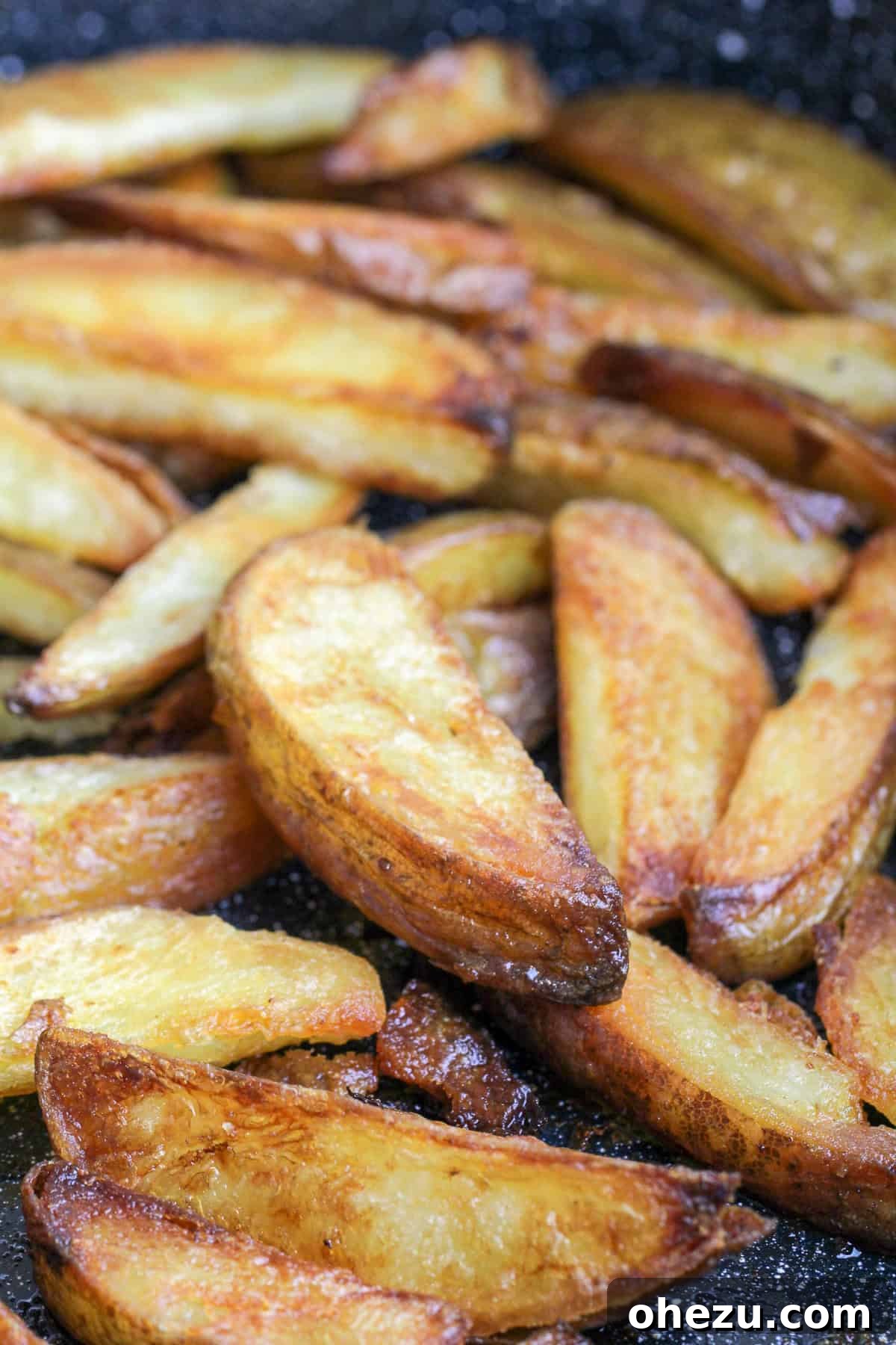 A hand reaching for a perfectly seasoned Crispy Baked Oven Fry from a bowl