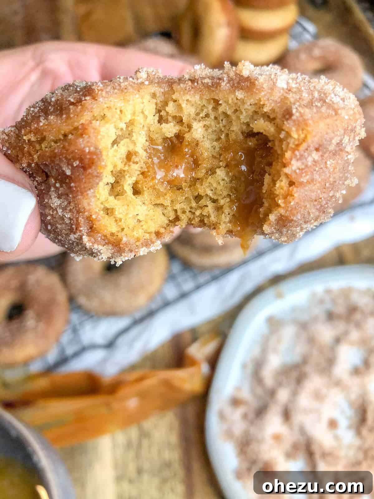 A stack of finished Caramel Apple Cider Donuts, drizzled with caramel and ready to eat.