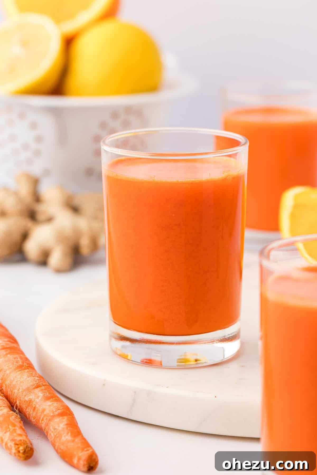 Vibrant carrot orange ginger juice in a clear glass, ready to be enjoyed.