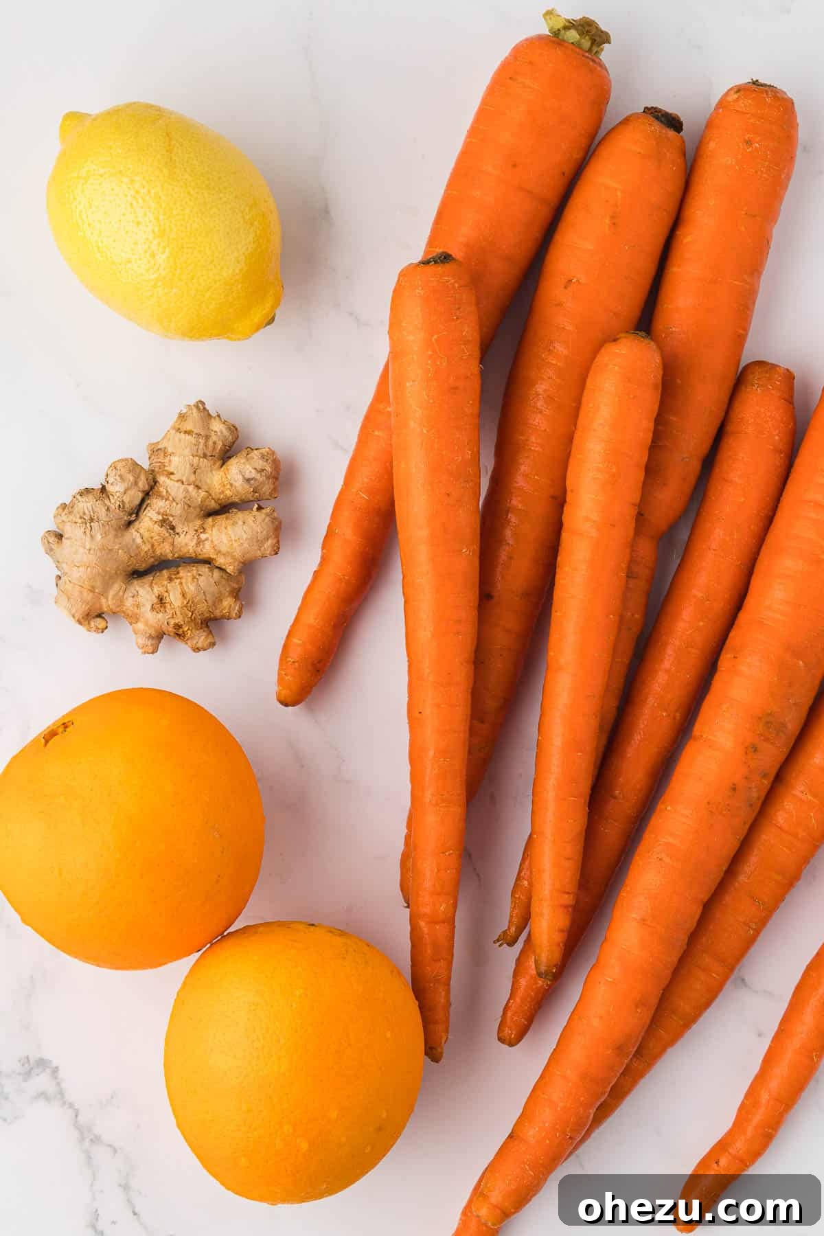 Fresh, vibrant ingredients for juicing: whole carrots, bright oranges, a zesty lemon, and a piece of aromatic ginger.