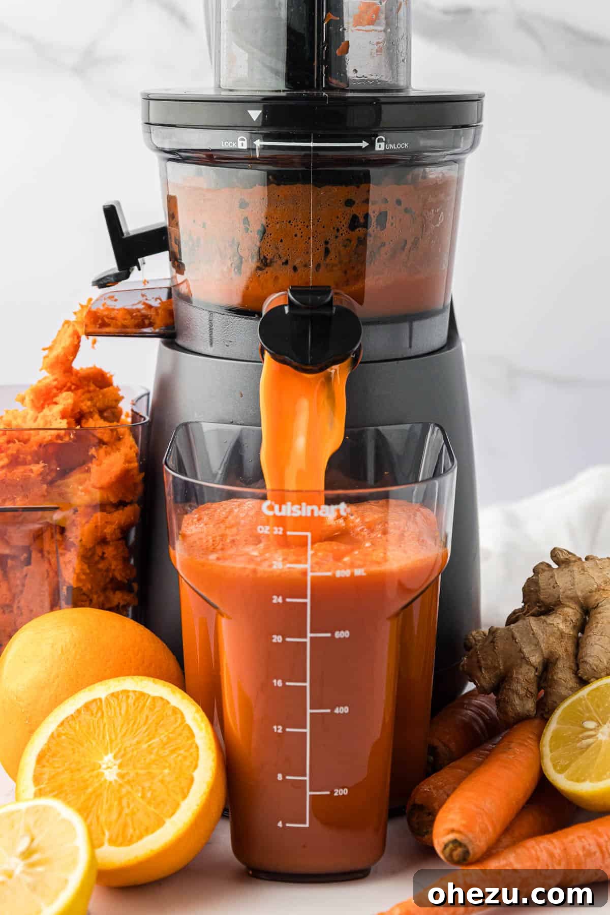 Freshly extracted carrot orange ginger juice pouring from a juicer into a collection container.