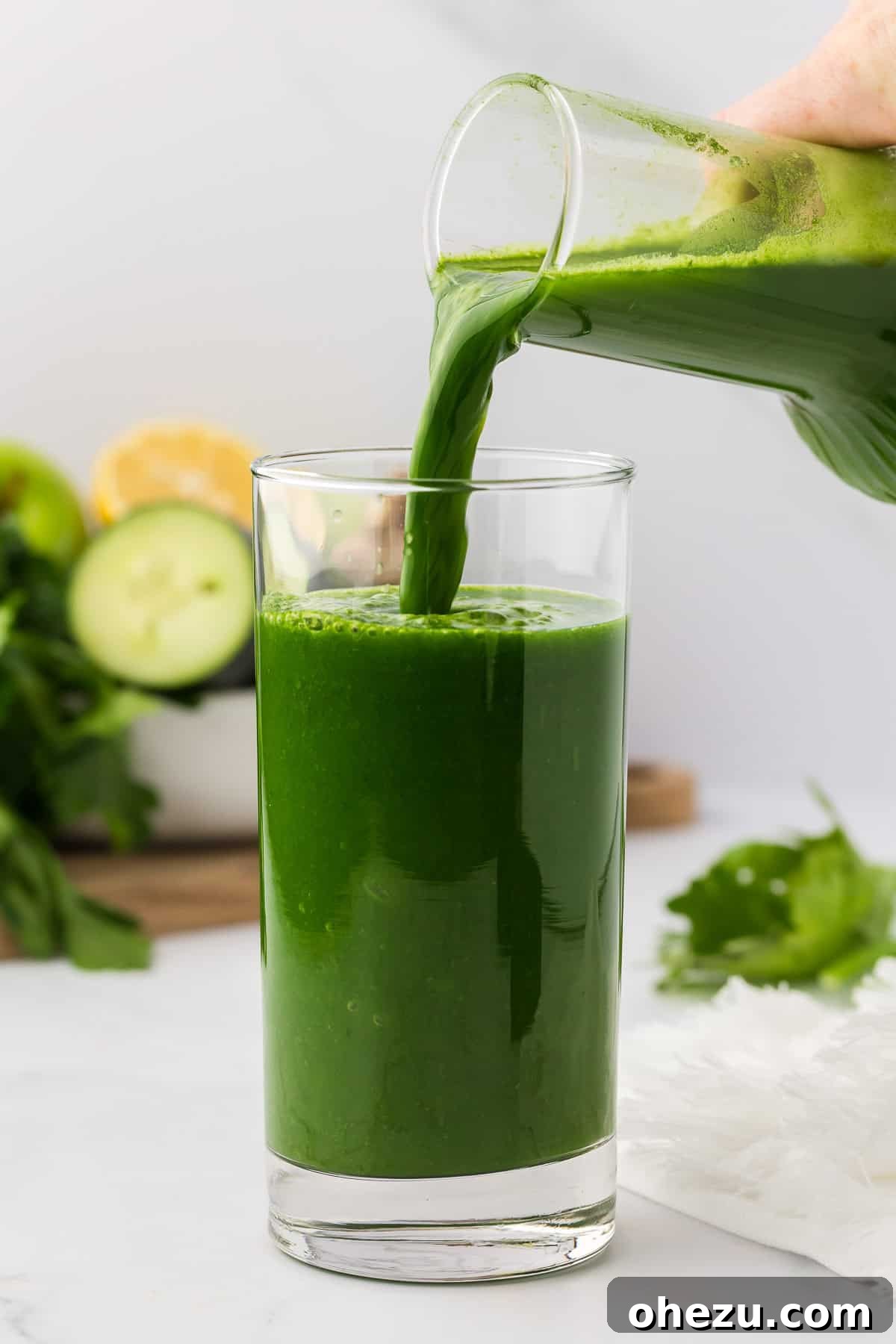 Pouring fresh vibrant green juice into a clear glass