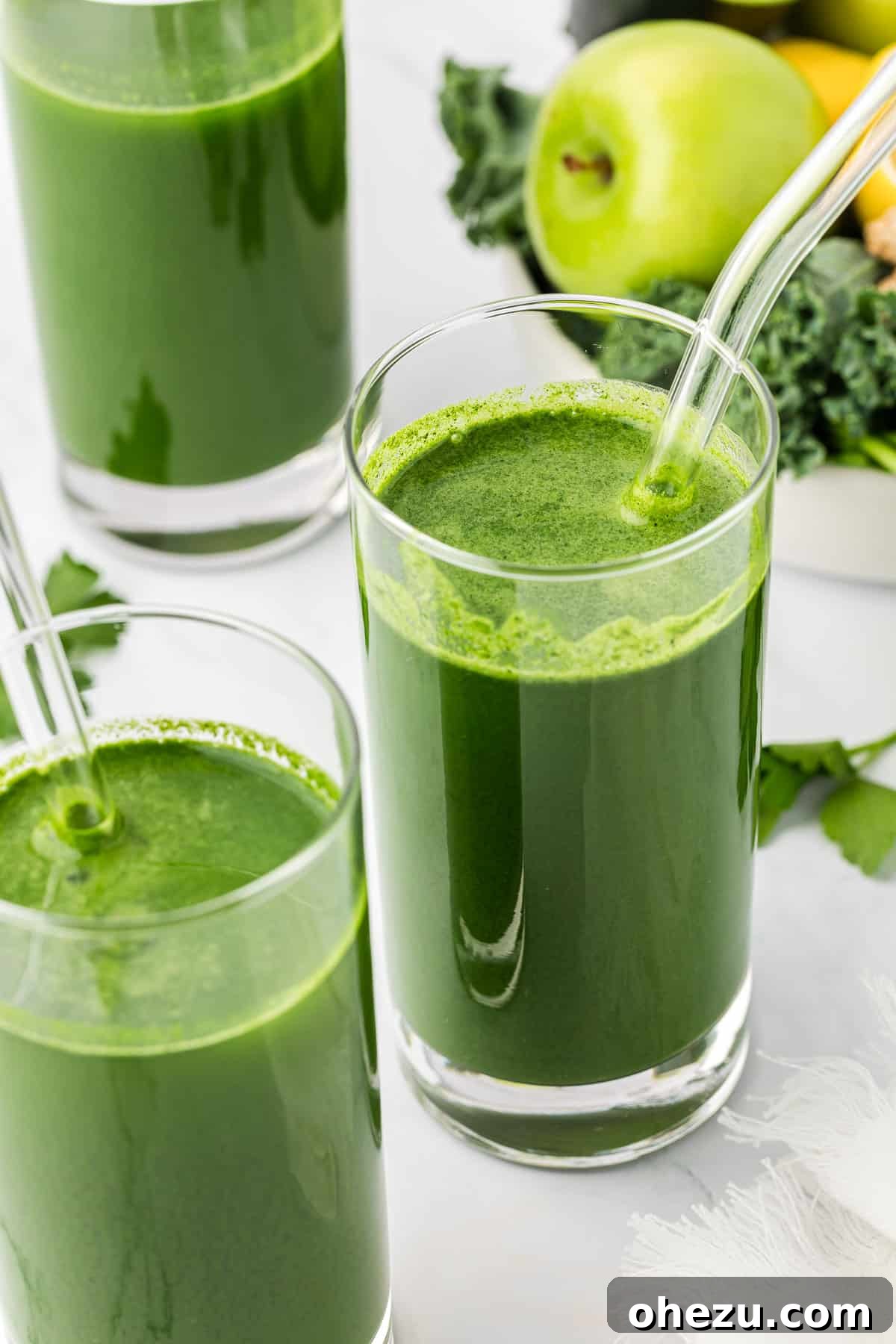 A tall glass of vibrant vegetable juice with a straw, ready for consumption