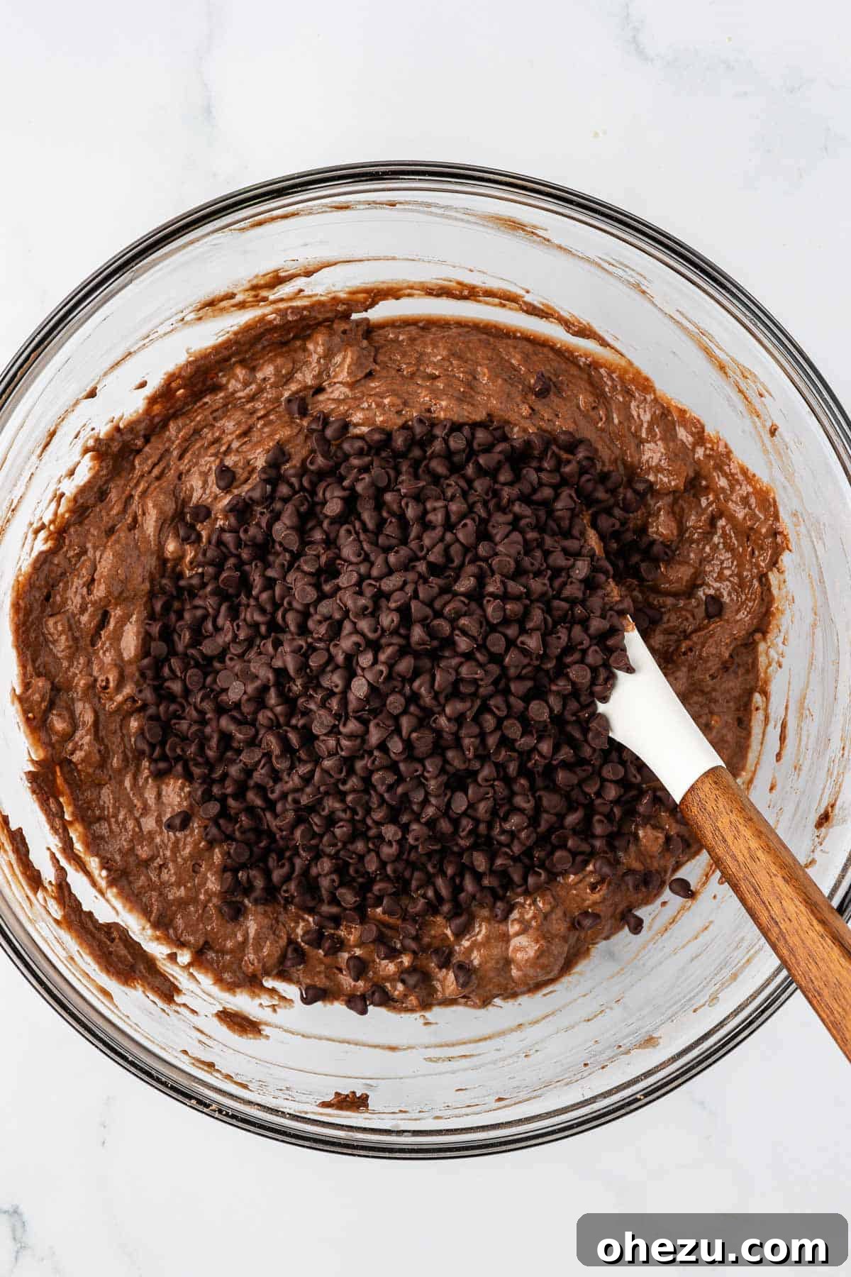 Nourishing Chocolate Mufflets 11 Adding a cup of mini chocolate chips into the muffin batter with a rubber spatula