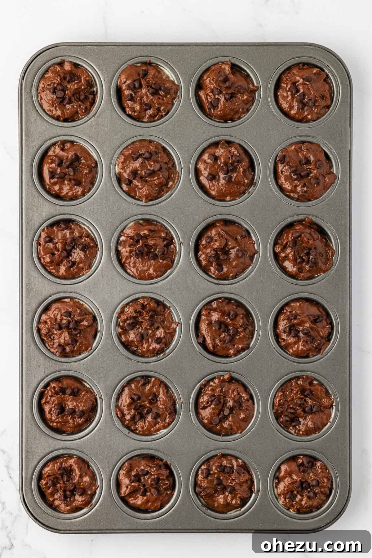Nourishing Chocolate Mufflets 13 Chocolate muffin batter being scooped into a mini muffin tin, filling each cavity precisely