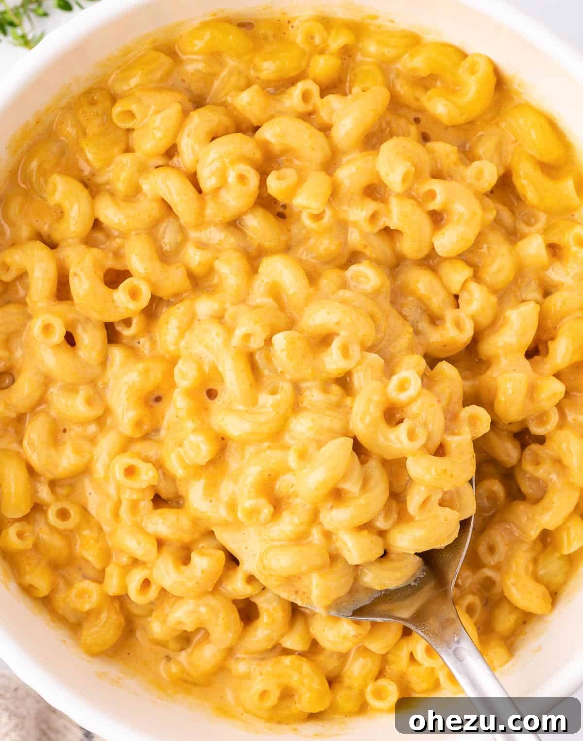 A vibrant bowl of butternut squash mac and cheese with a serving spoon, ready to be enjoyed.