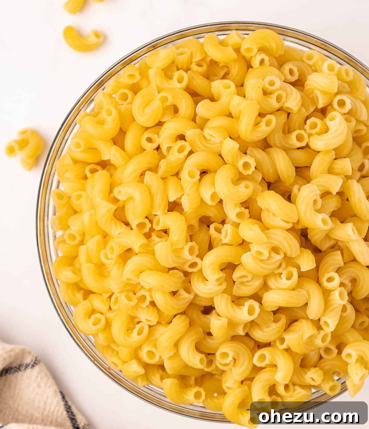Cooked elbow macaroni noodles resting in a large bowl, waiting for the creamy sauce.