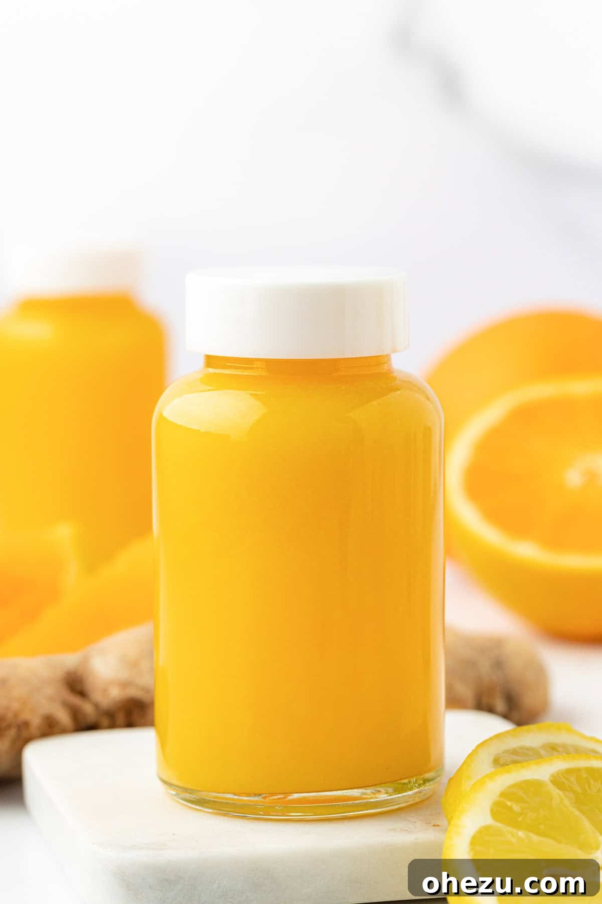 Various small jars of citrus ginger immunity shots arranged appealingly on a wooden surface.