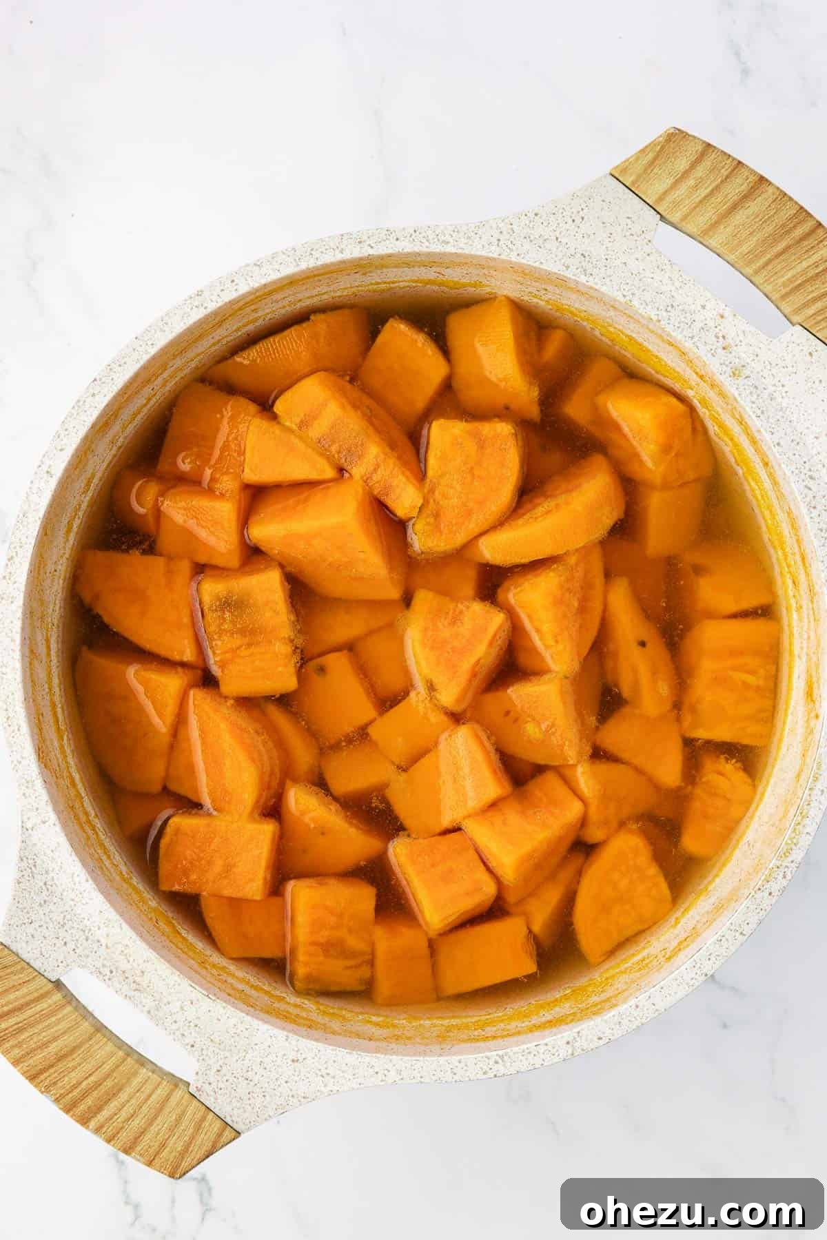 Close-up of boiled, tender sweet potato chunks in a saucepan, ready for mashing.