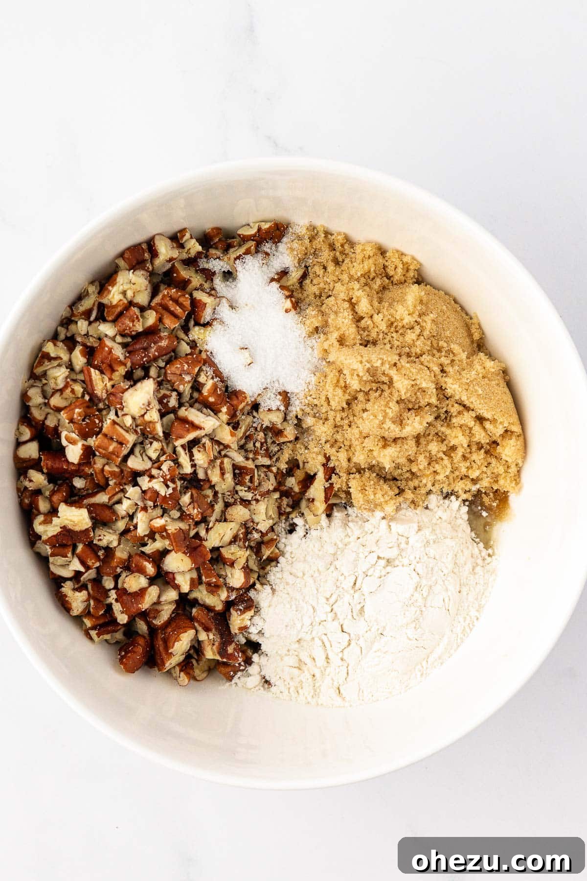 A bowl containing all the dry and wet ingredients for the pecan crumble topping, including melted butter, brown sugar, flour, salt, and chopped pecans.