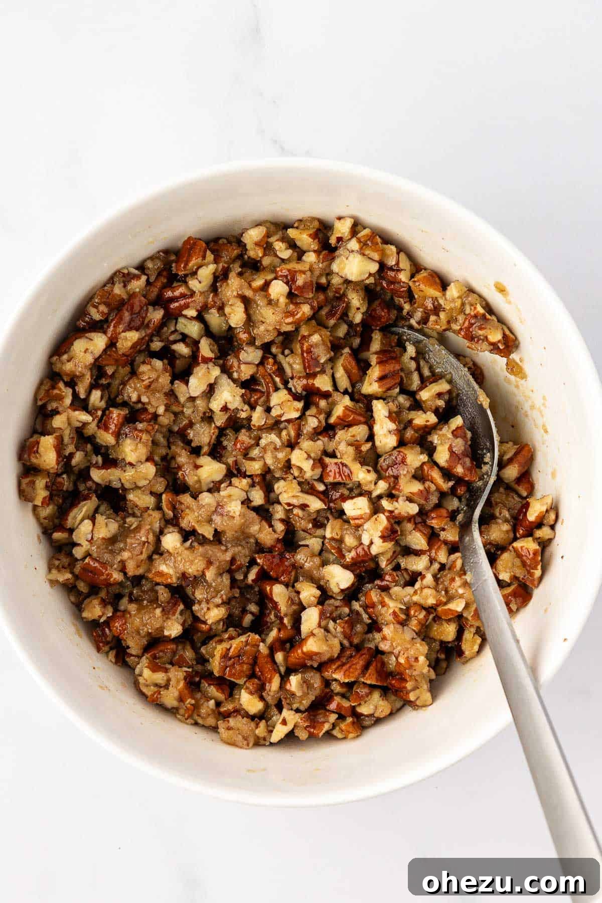 The fully mixed pecan topping in a bowl, a coarse mixture of chopped pecans and a buttery brown sugar crumble.
