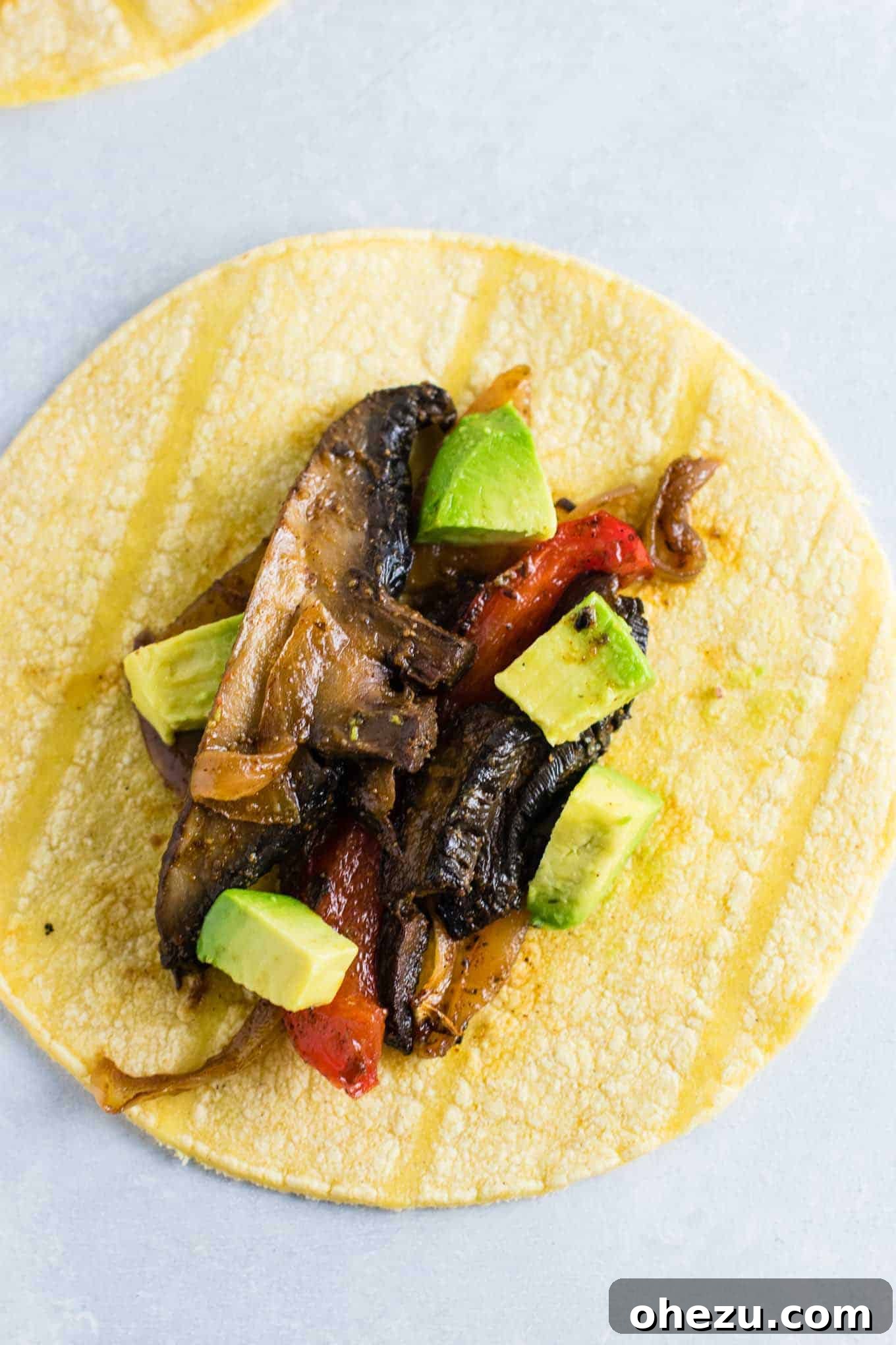 Sizzling Portobello Fajitas 3 Close-up of perfectly cooked portobello mushroom fajitas, served on a corn tortilla with creamy diced avocado