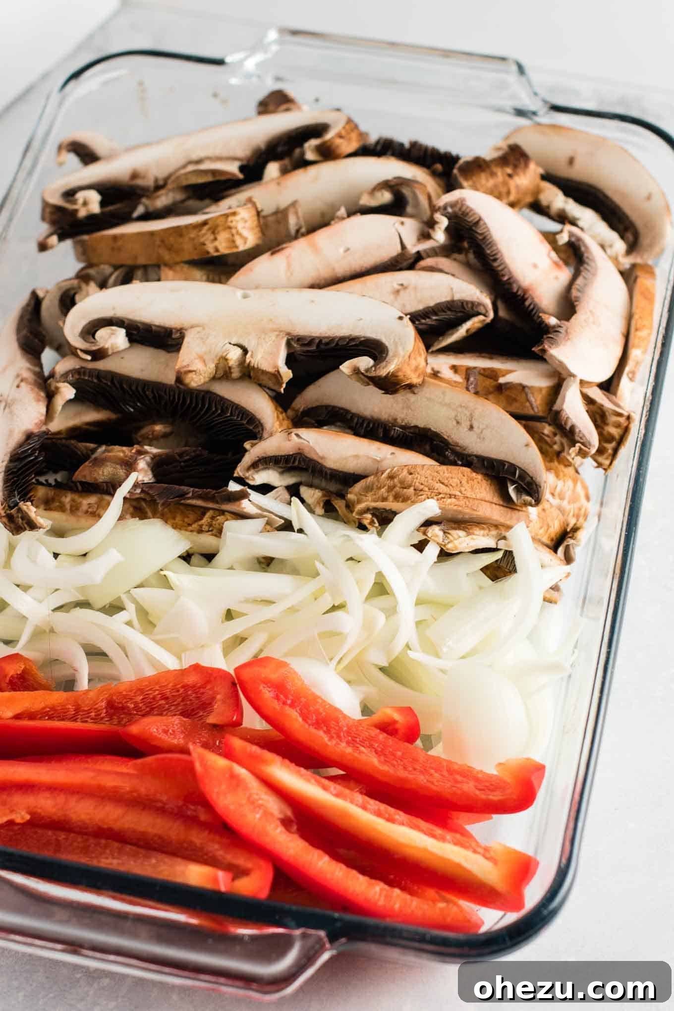 Sizzling Portobello Fajitas 4 Sliced portobello mushroom caps, onion, and red bell pepper coated in spices and olive oil, ready for roasting in a glass baking dish