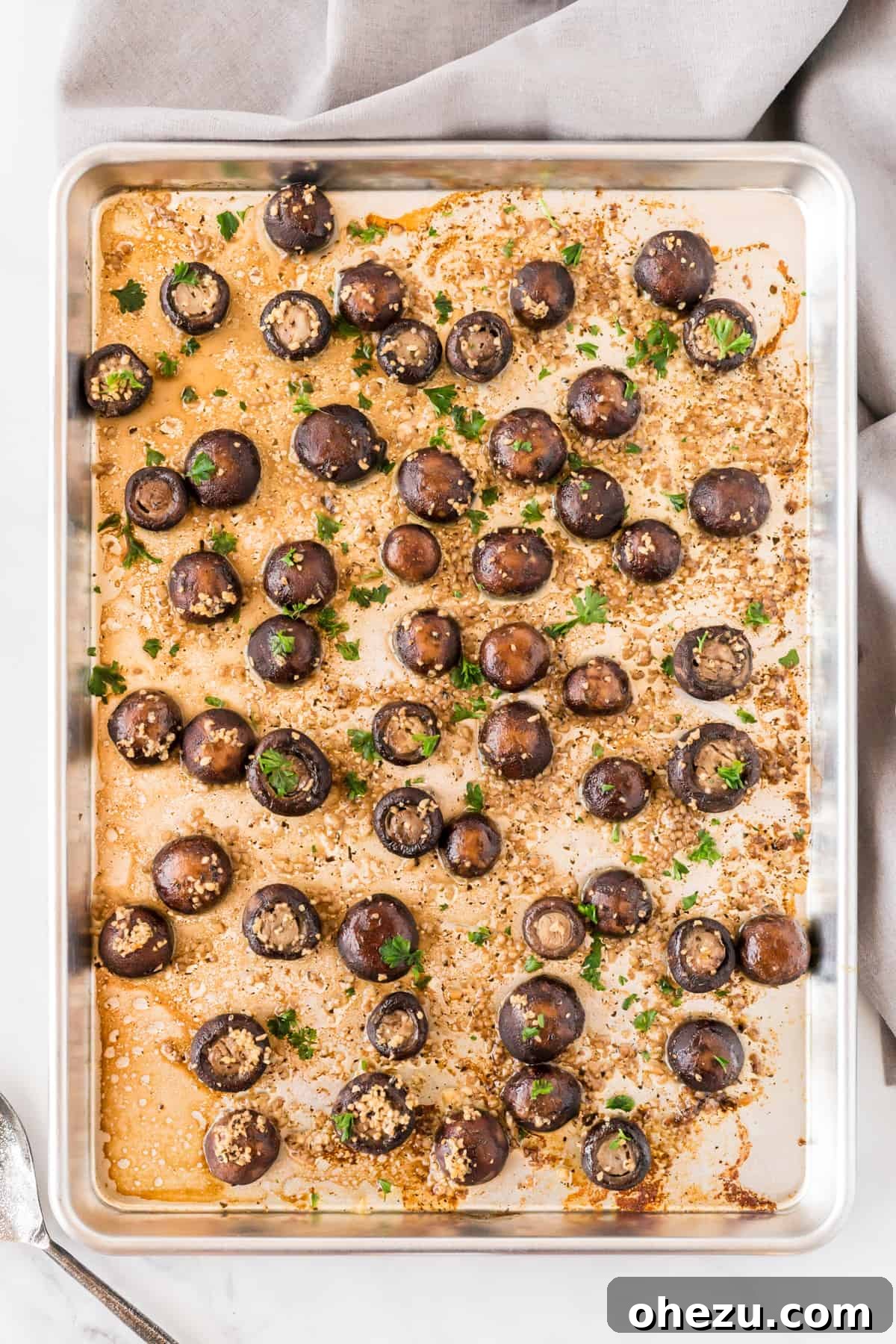 Overhead view of roasted garlic mushrooms on a sheet pan, ready to be served.
