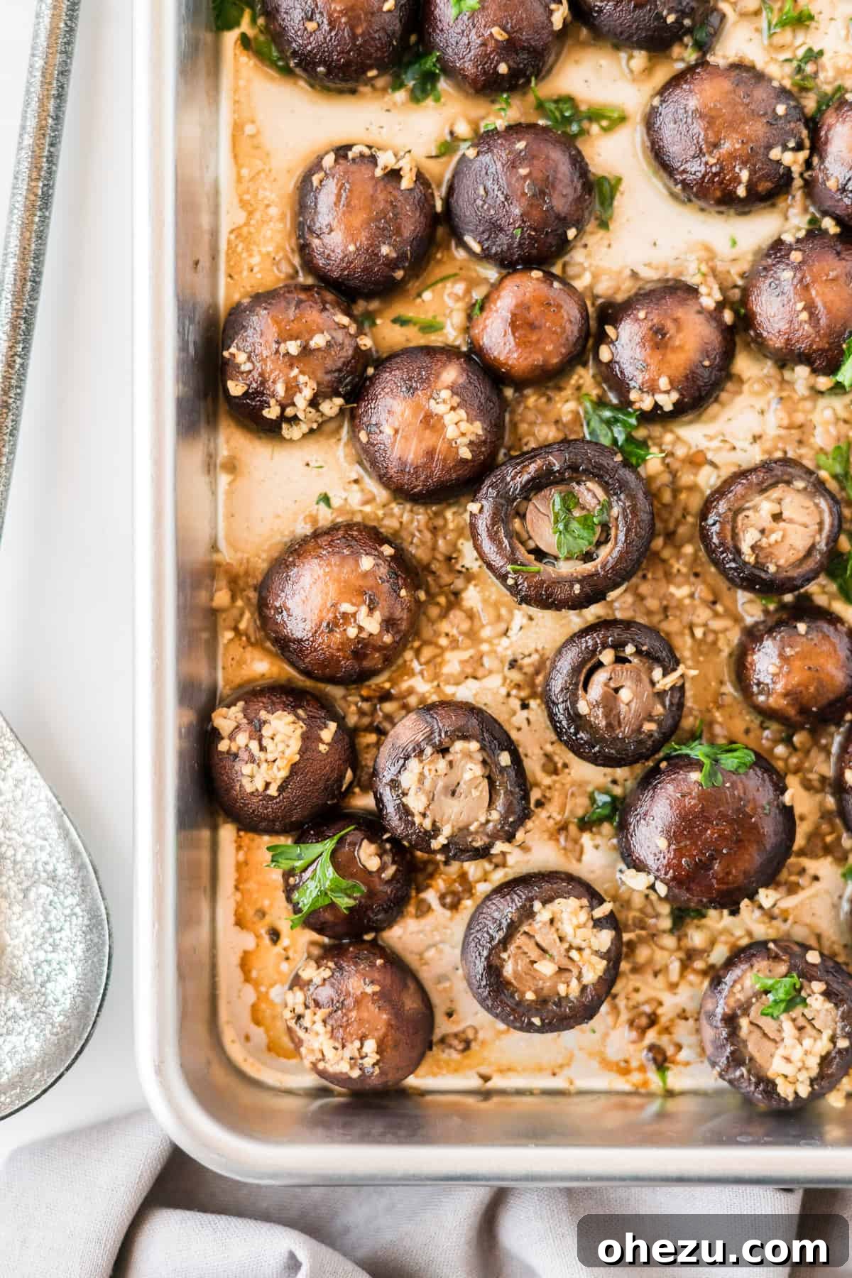A close-up shot of roasted garlic mushrooms in a serving bowl, garnished with fresh parsley.