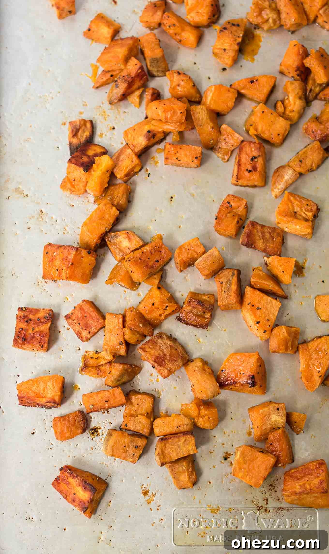 A large pan of perfectly roasted sweet potato cubes, showing off their crispy exteriors and rich color.
