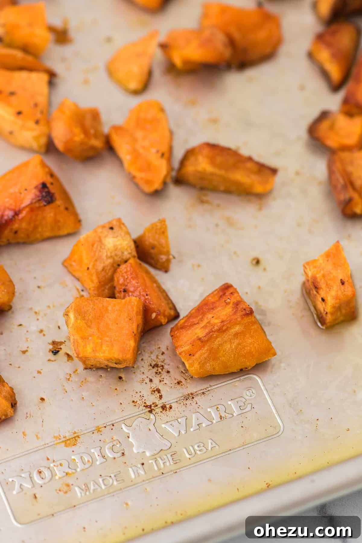 A rustic bowl filled with roasted sweet potatoes, garnished with fresh herbs, showcasing their inviting texture.