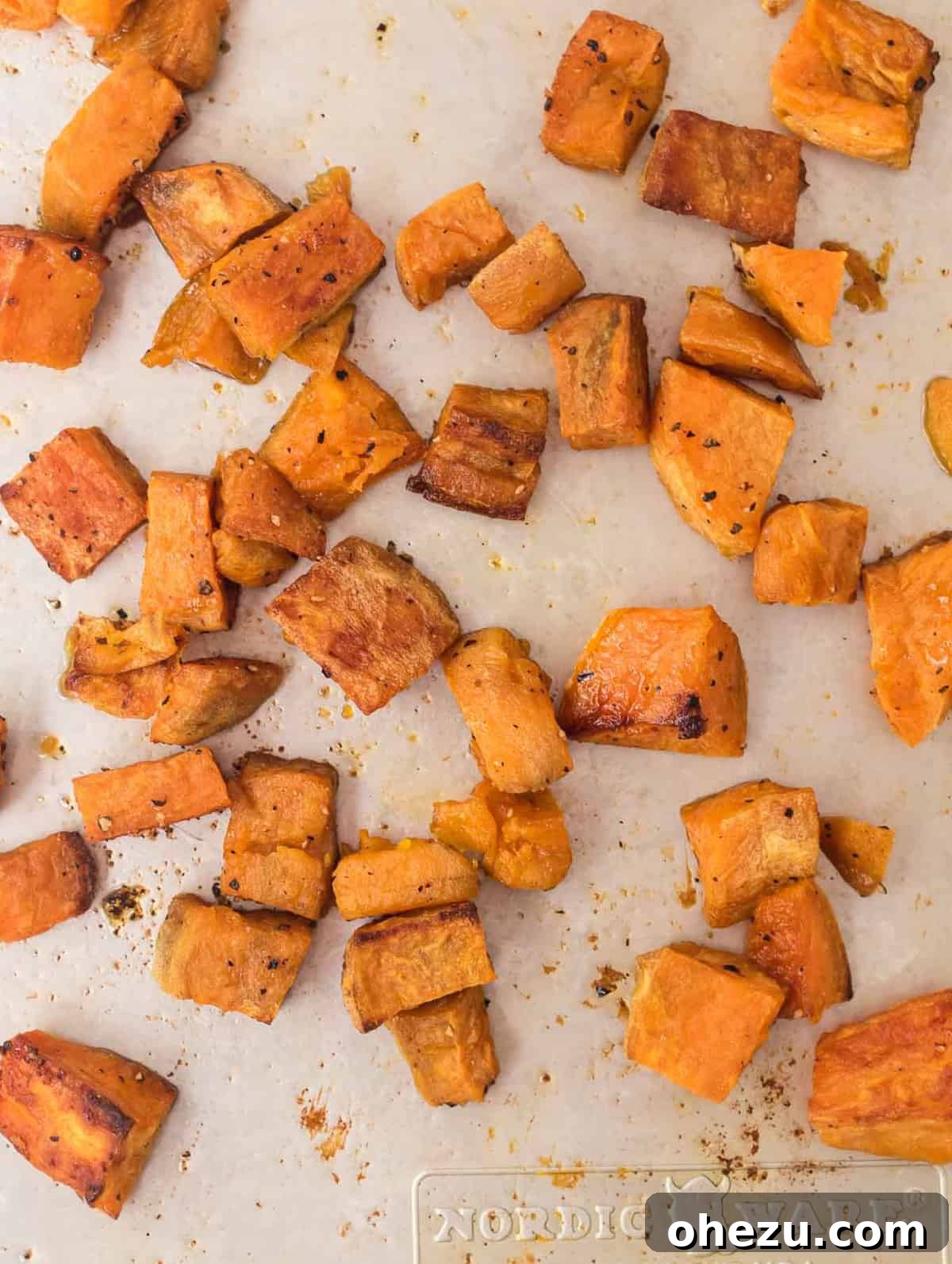 Roasted sweet potatoes, cubed and golden, cooling on a baking sheet after being removed from the oven.