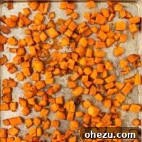 Close-up of crispy roasted sweet potato cubes on a baking sheet, ready to serve.