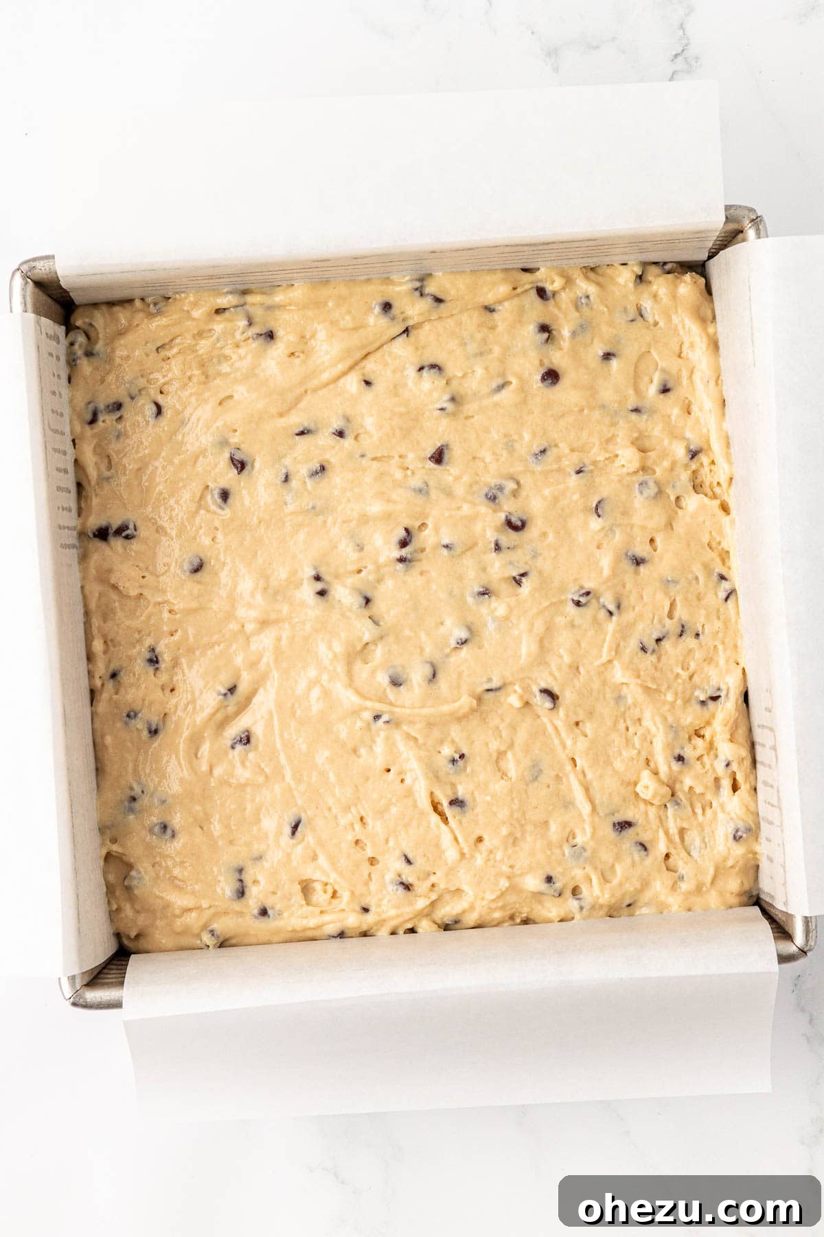 Tangy Greek Yogurt Treat Cake 15 Greek yogurt cake batter poured into a parchment-lined 8x8 baking dish, ready for the oven