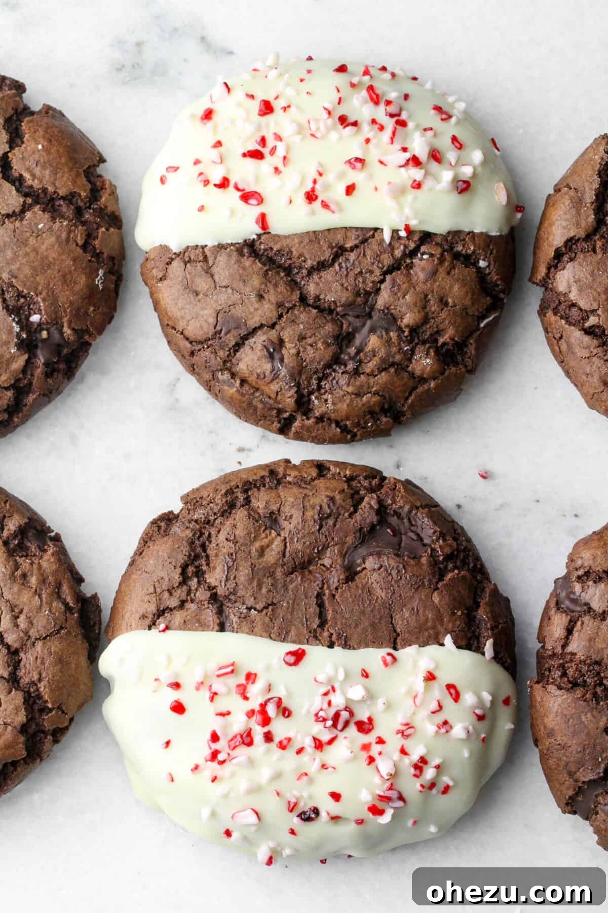 Close-up view of chocolate cookies expertly dipped in white chocolate and garnished with festive crushed peppermint candies.