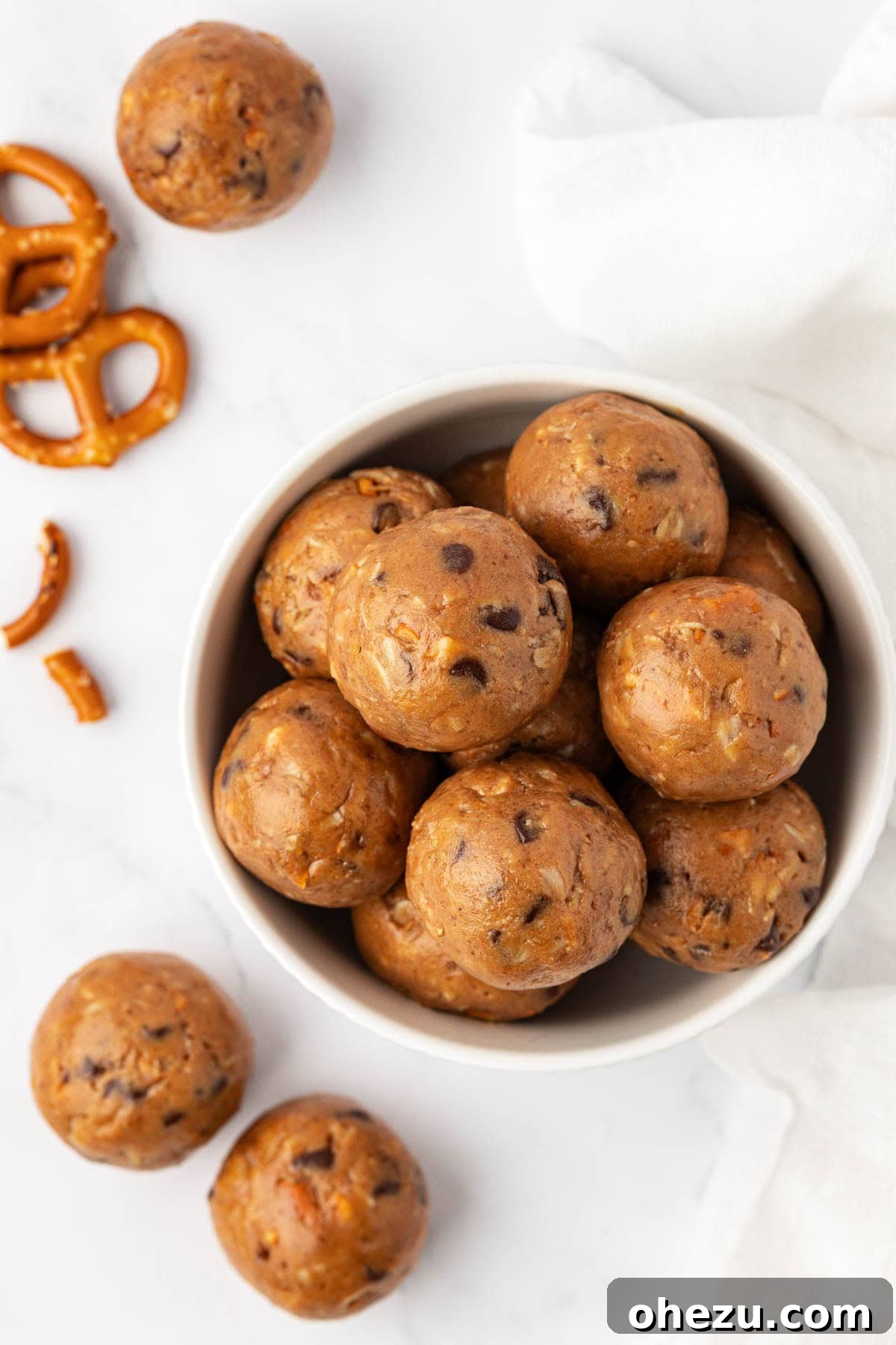 Mixing bowl with peanut butter pretzel energy bite ingredients being stirred with a spatula