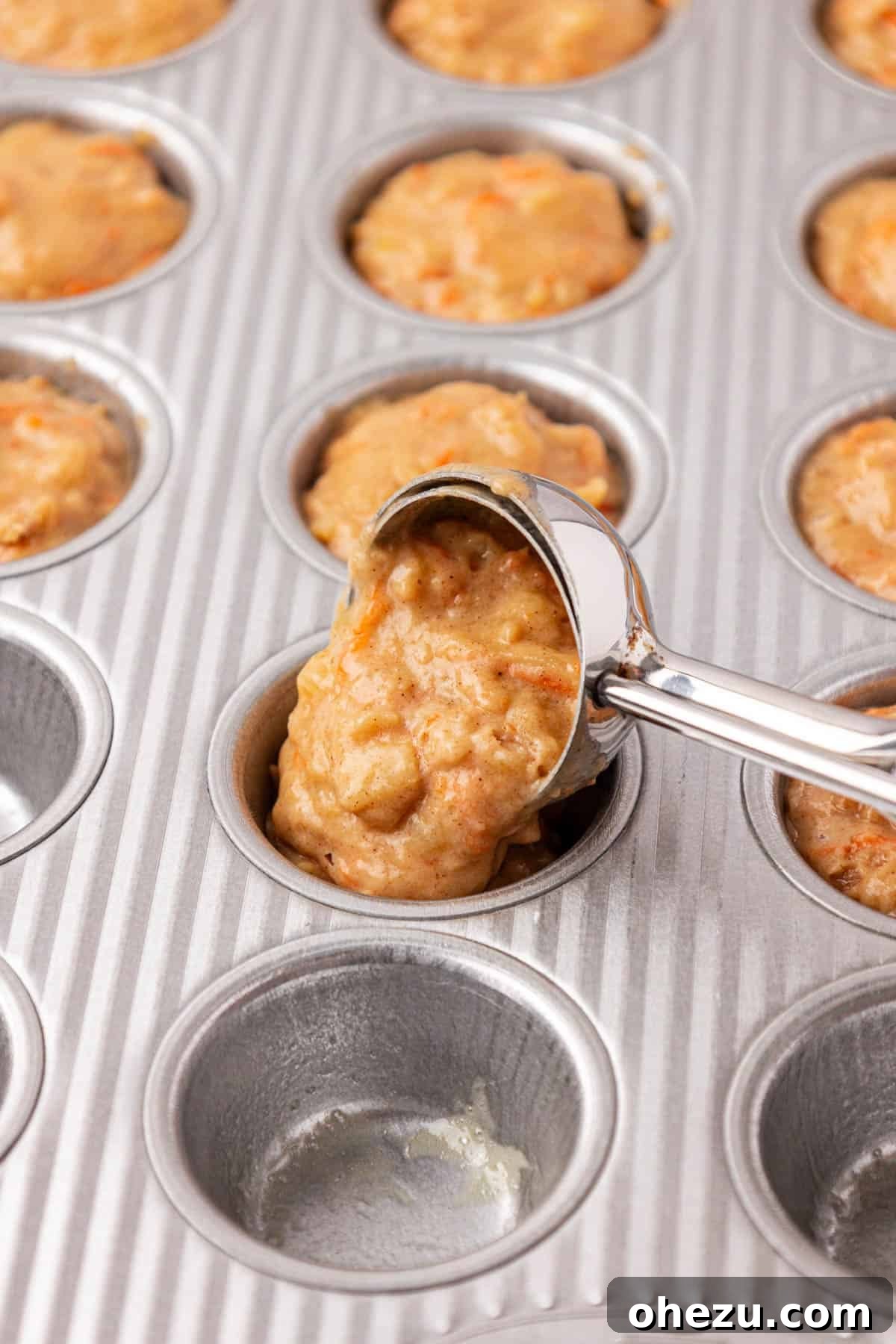 Poppable Perfection Muffins 13 A mini cookie scoop carefully portioning ABC muffin batter into a greased mini muffin tin.