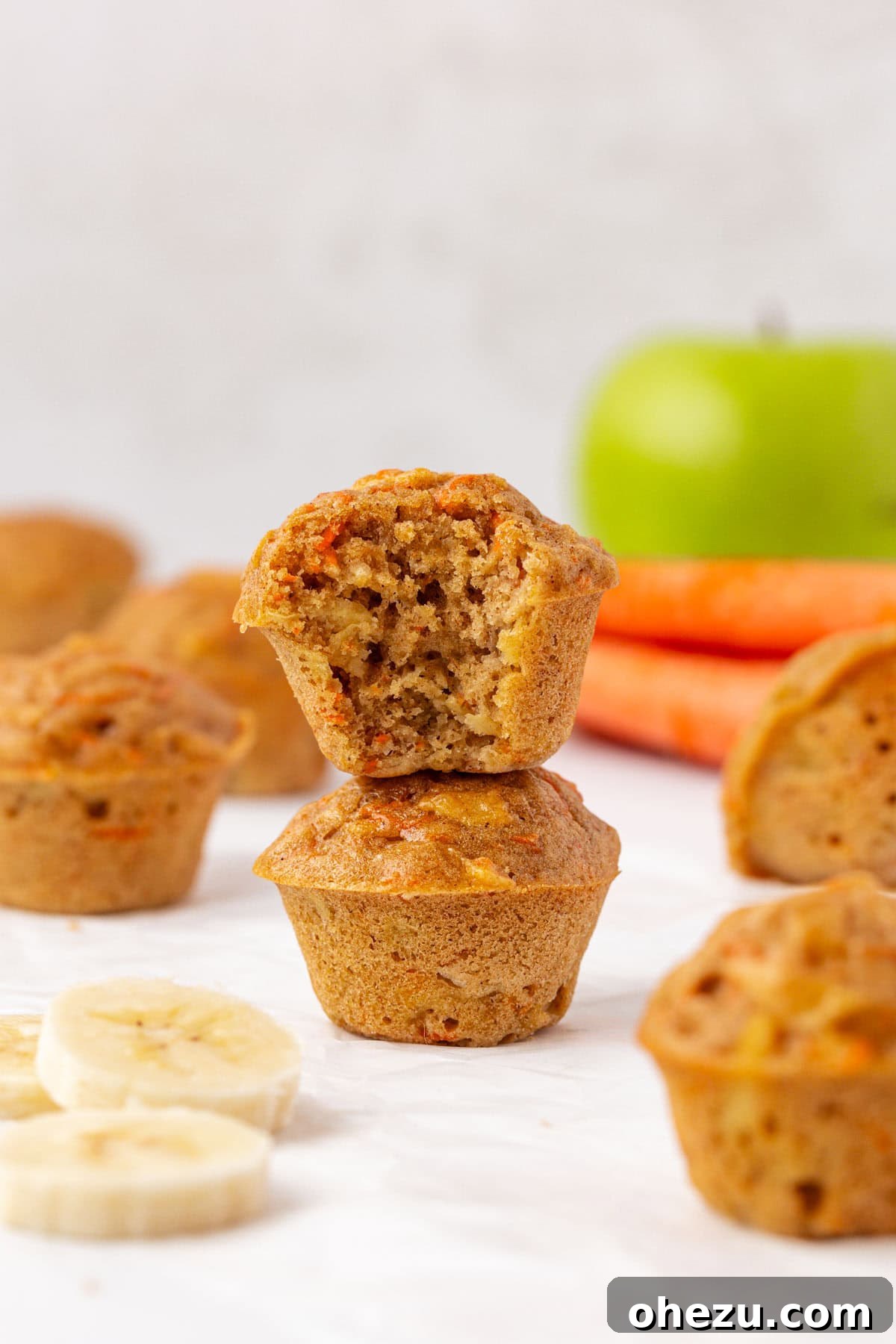 Poppable Perfection Muffins 3 A close-up of an ABC mini muffin with a bite taken out, revealing the moist interior speckled with apple, banana, and carrot pieces.