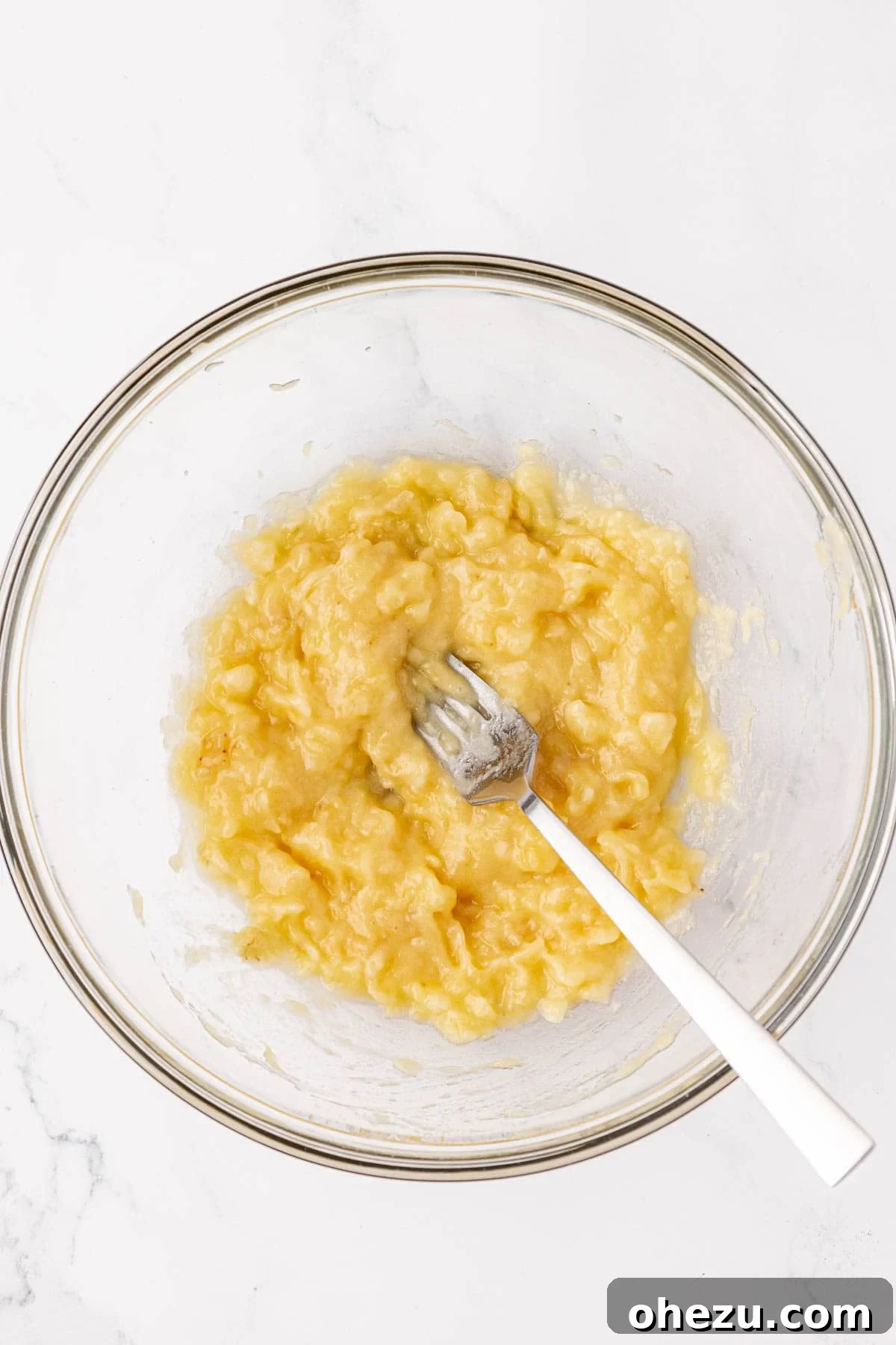 Poppable Perfection Muffins 8 Well-mashed banana in a mixing bowl, showing a smooth and creamy texture without lumps.