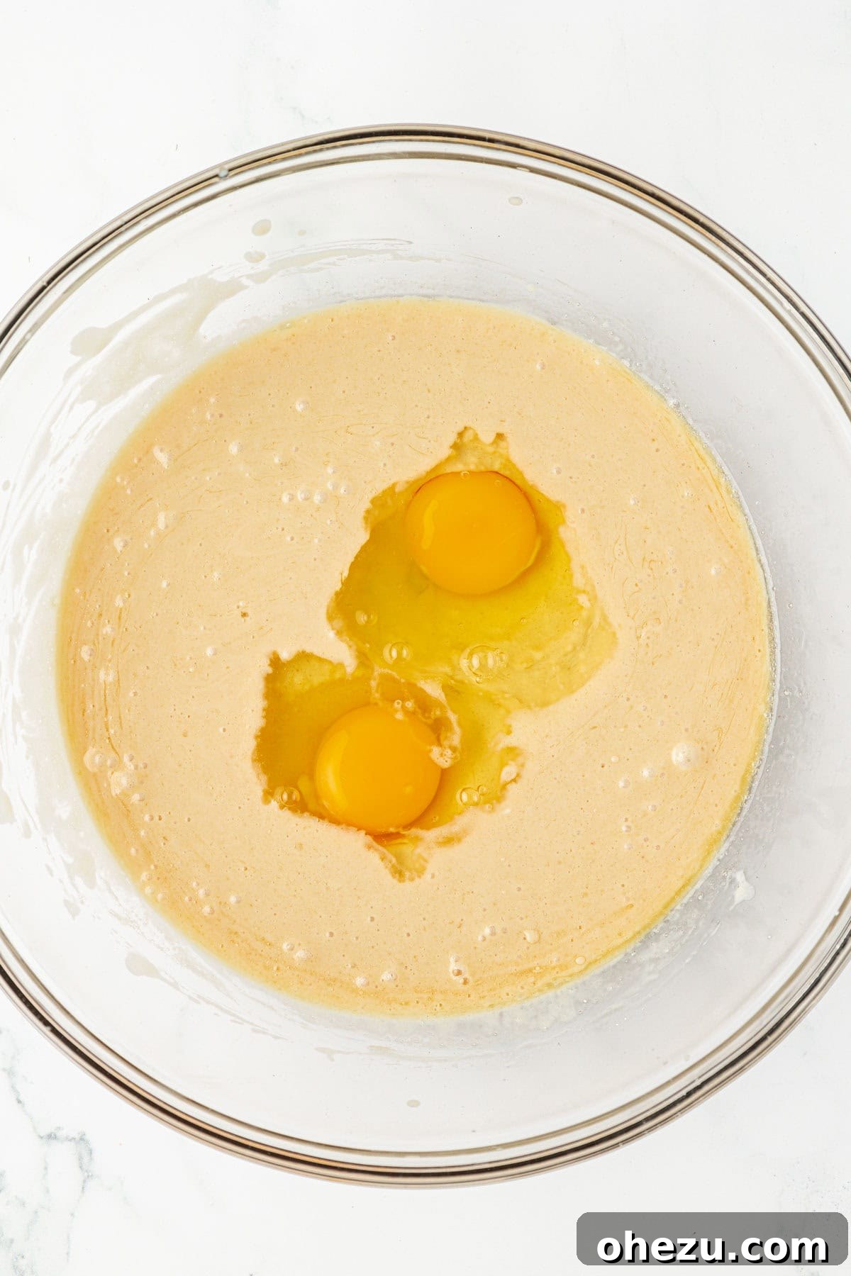 Adding eggs to the wet ingredients for the cake