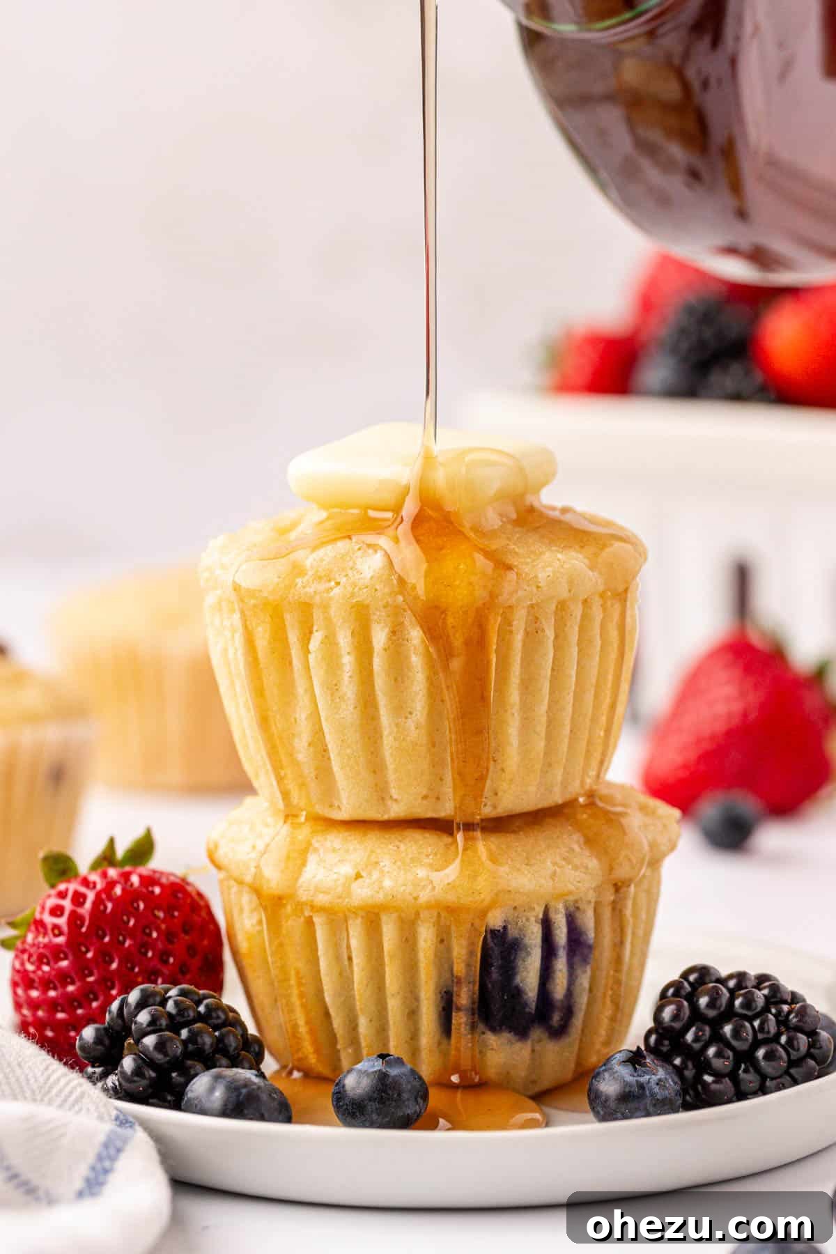 Golden brown pancake muffins topped with a pat of butter and a drizzle of maple syrup, ready for a delicious breakfast.