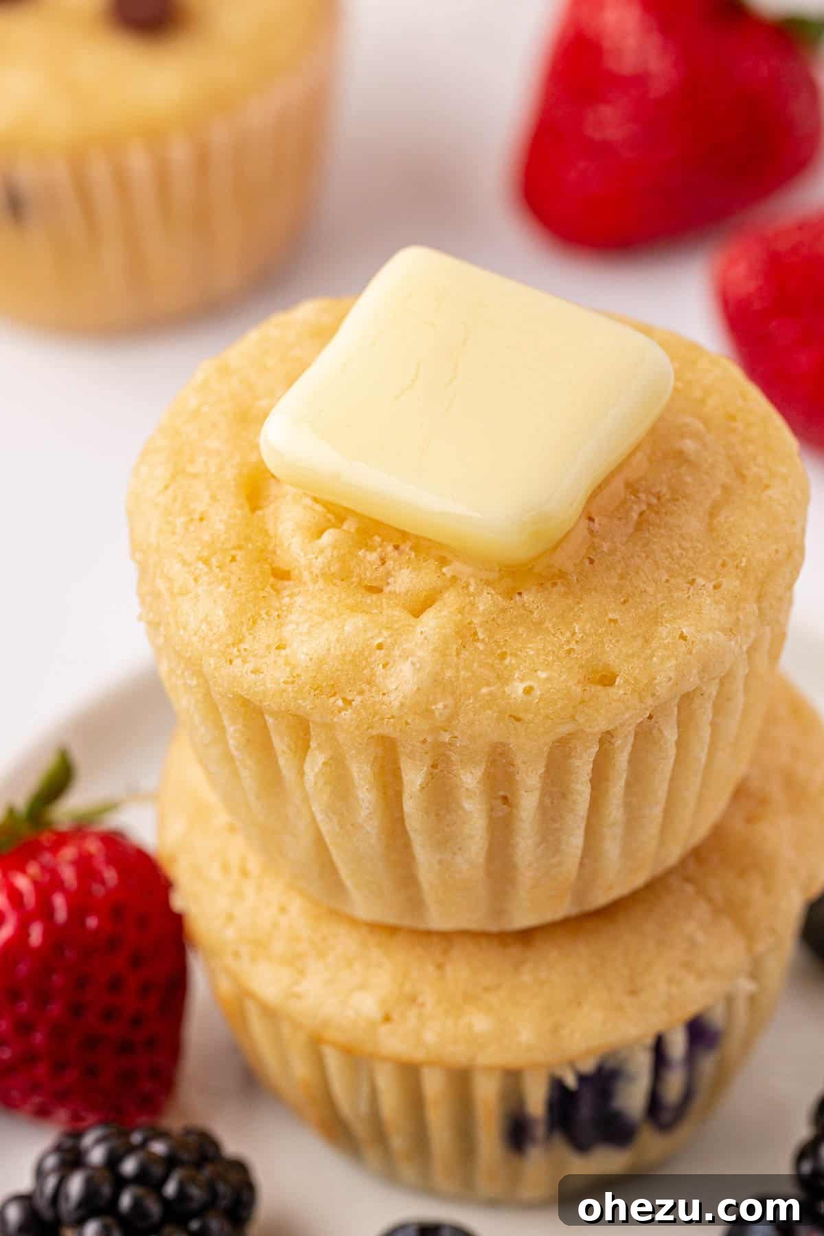 A close-up of pancake muffins, some with chocolate chips, some plain, topped with melted butter.