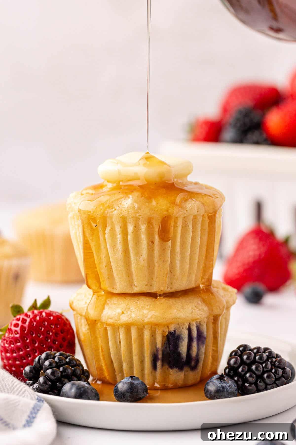 Two pancake muffins, generously topped with butter and dripping maple syrup, presented beautifully.