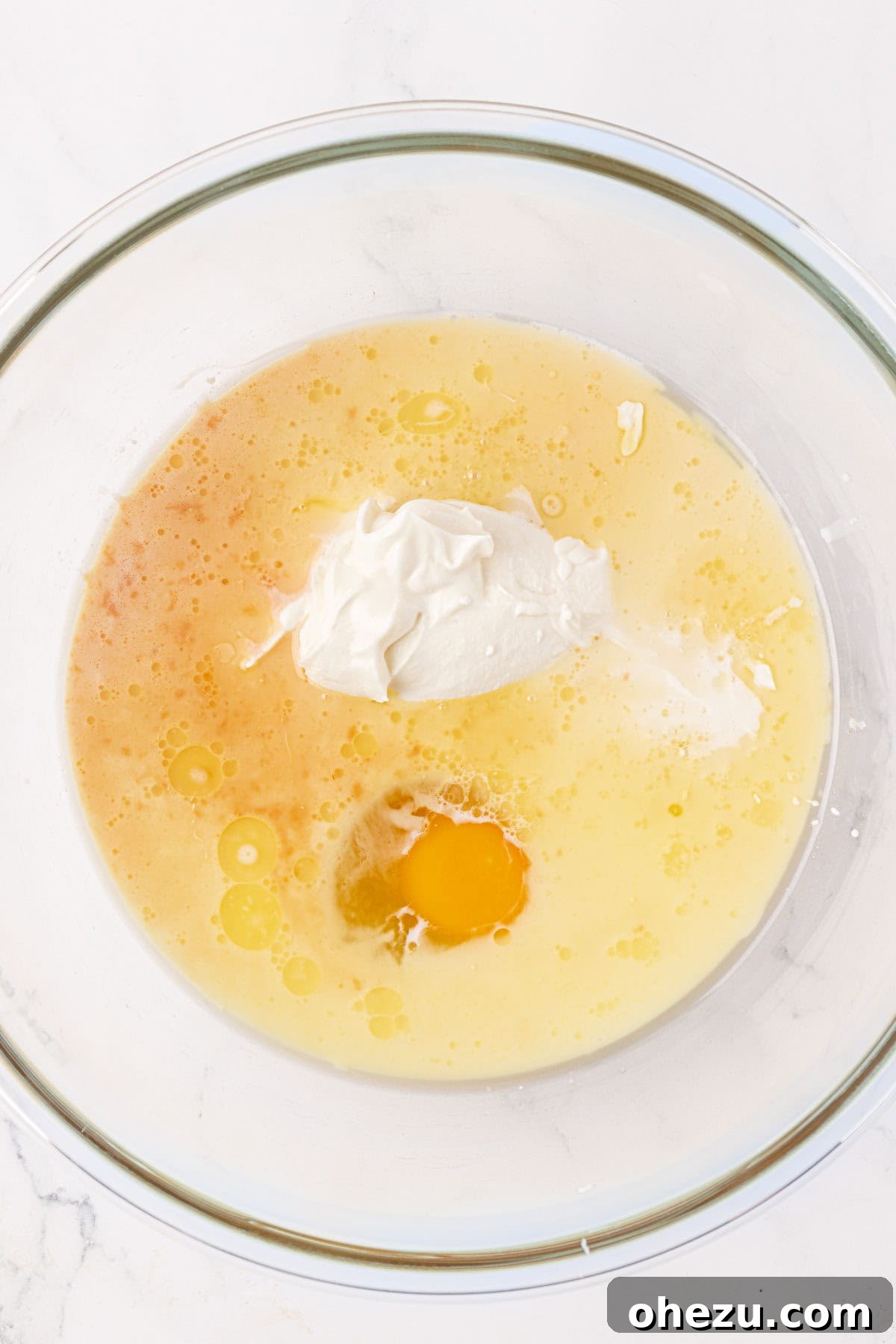 Wet ingredients for pancake muffins, including milk, yogurt, butter, egg, and vanilla extract, in a mixing bowl.