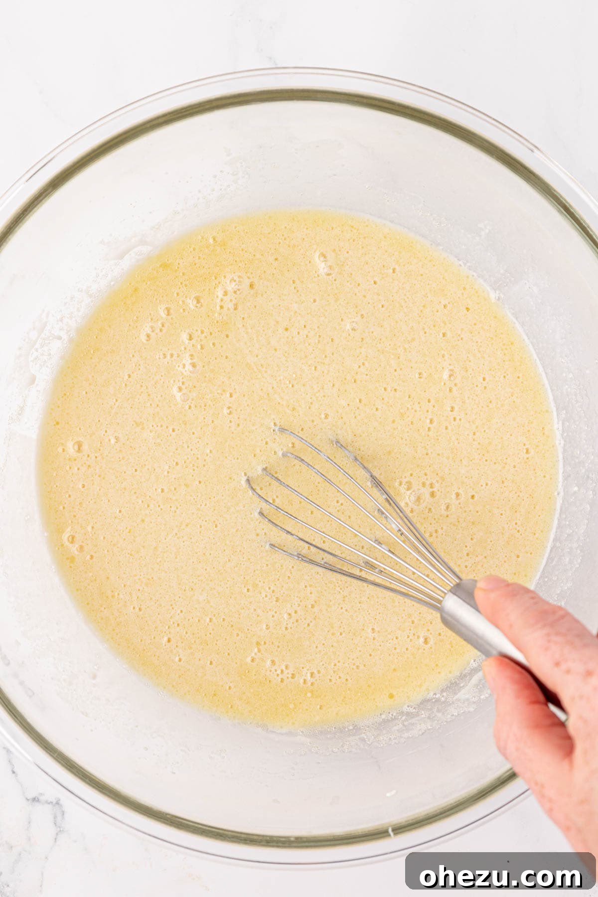 A whisk mixing the wet ingredients together in a bowl until smooth.