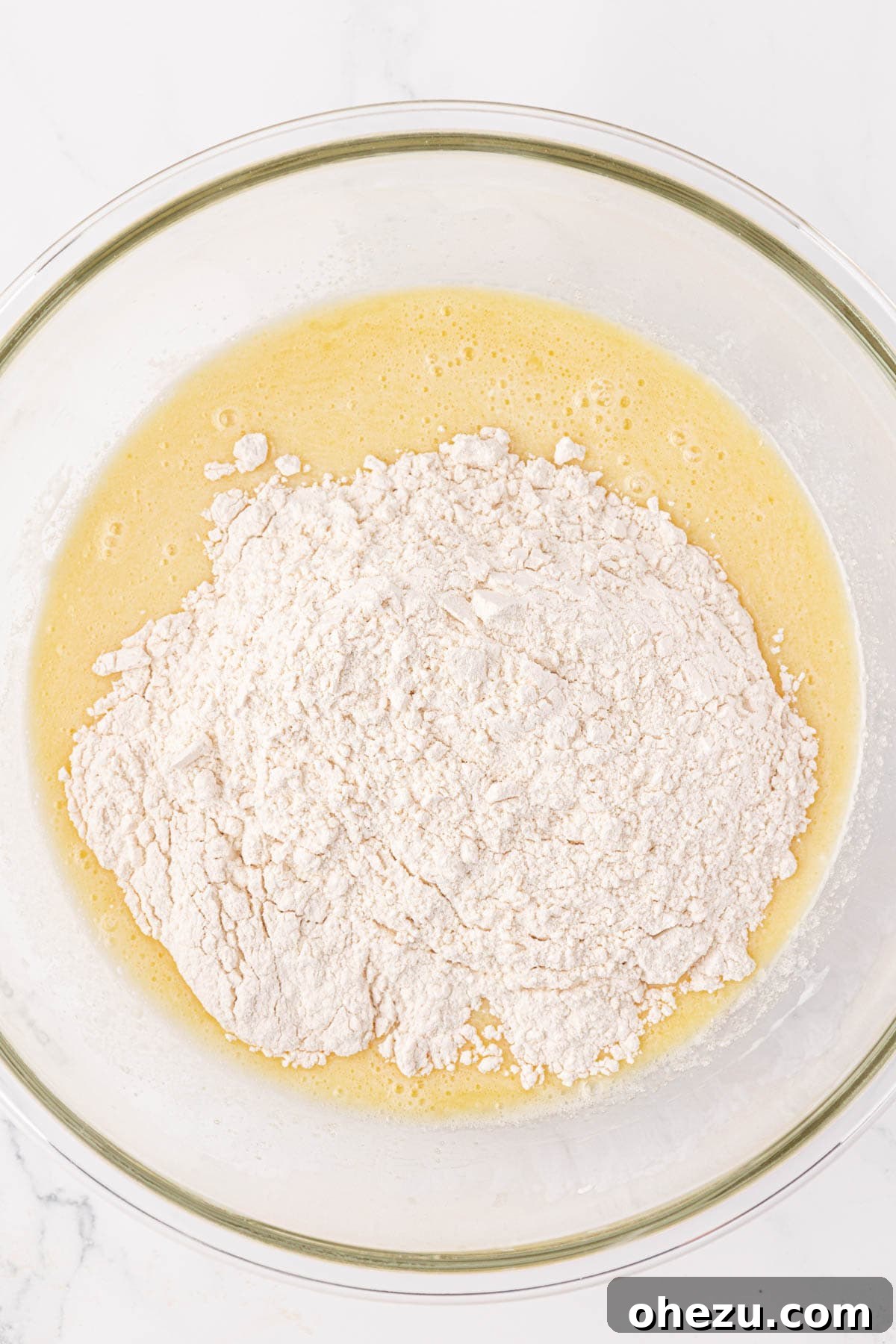 The process of adding dry ingredients into the bowl of wet ingredients for pancake muffin batter.