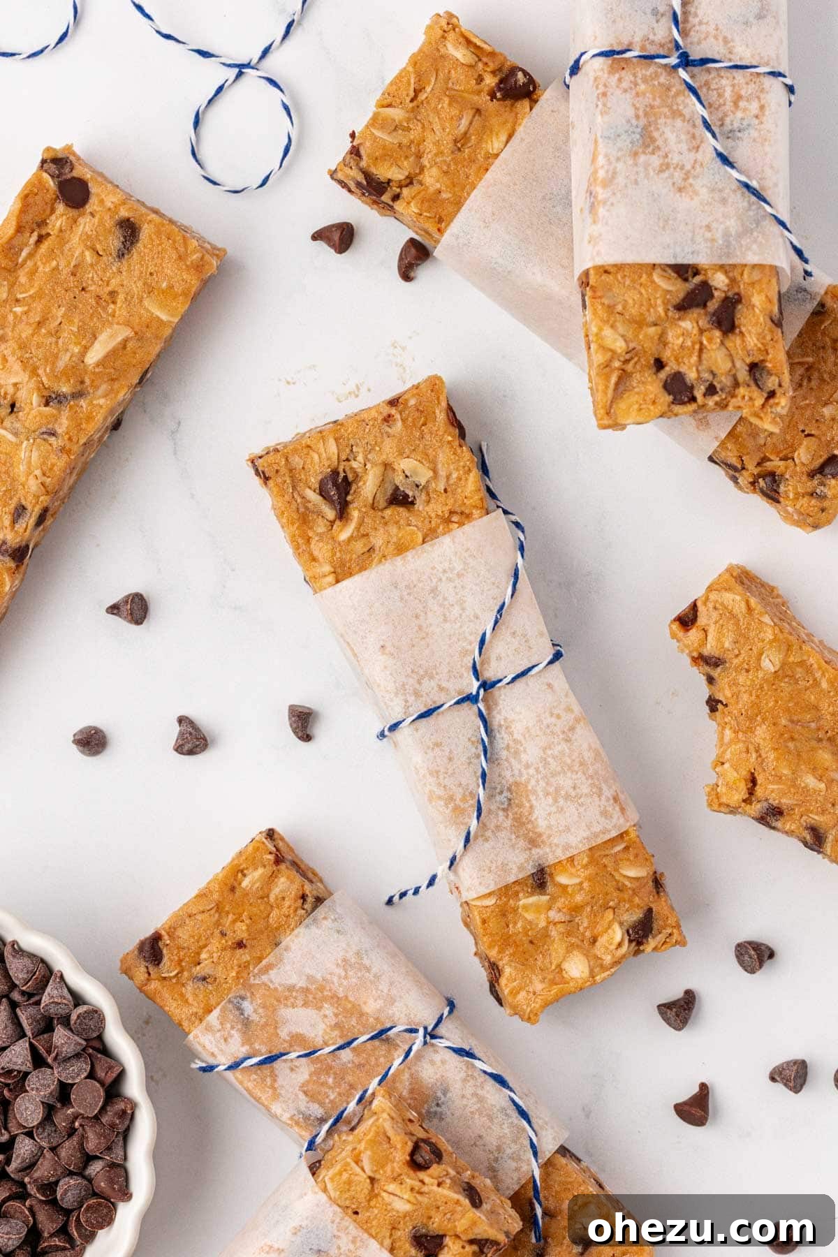 Close-up photograph of a protein granola bar, highlighting its soft, chewy texture with visible rolled oats and melted mini chocolate chips.