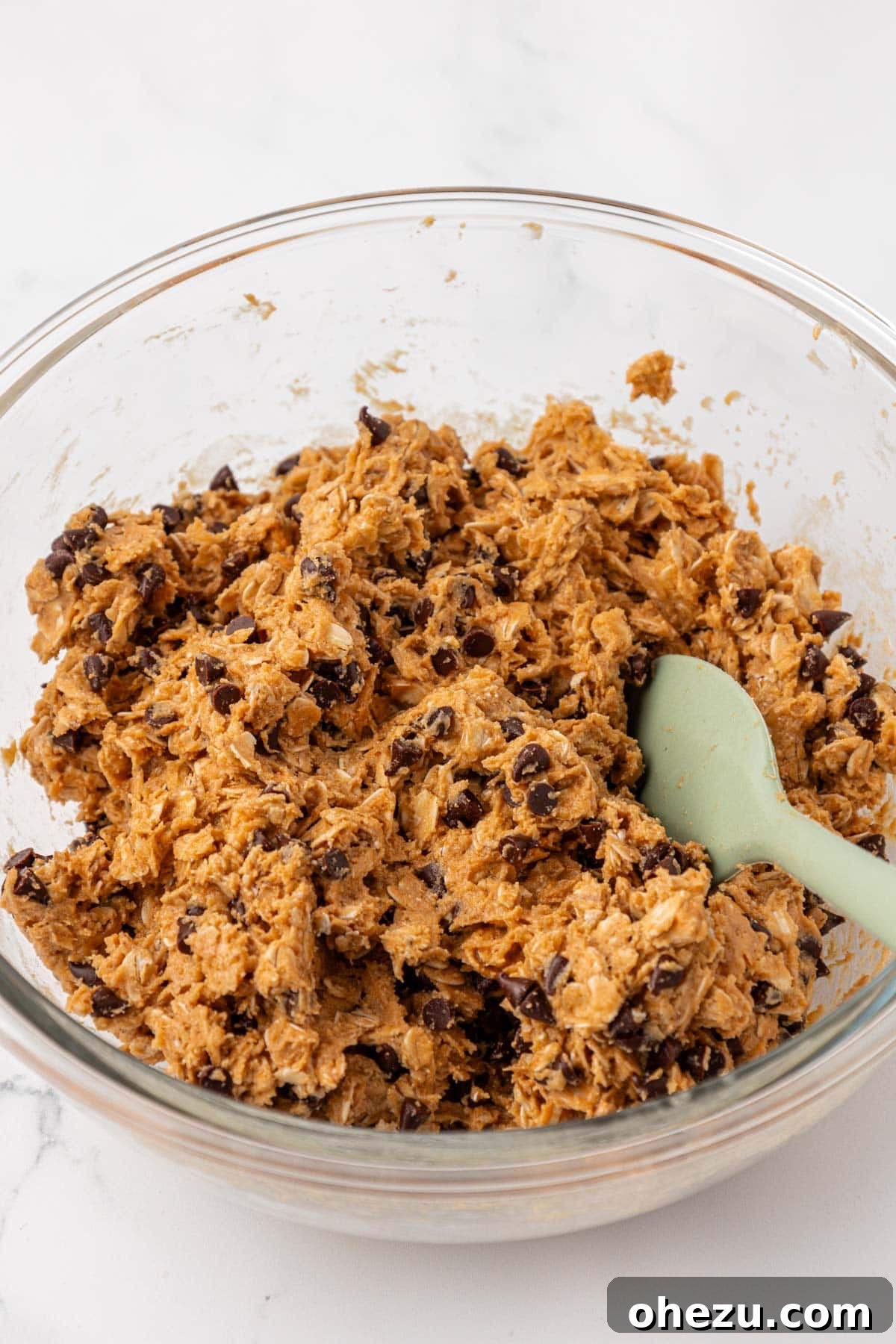 The final protein granola bar batter, showcasing mini chocolate chips thoroughly and evenly mixed in, creating a ready-to-press mixture.