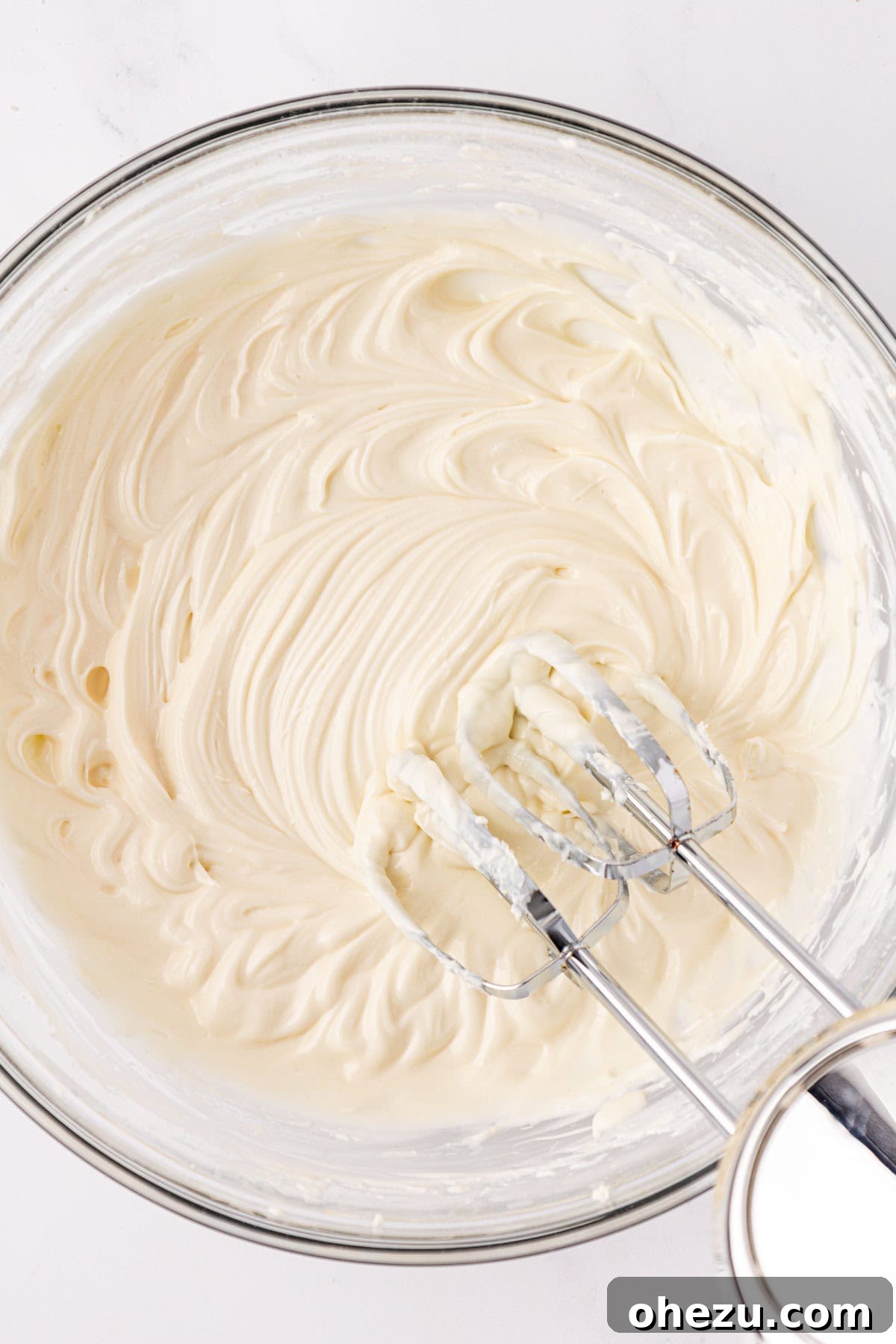 Smooth and creamy cream cheese frosting in a bowl, perfectly mixed.