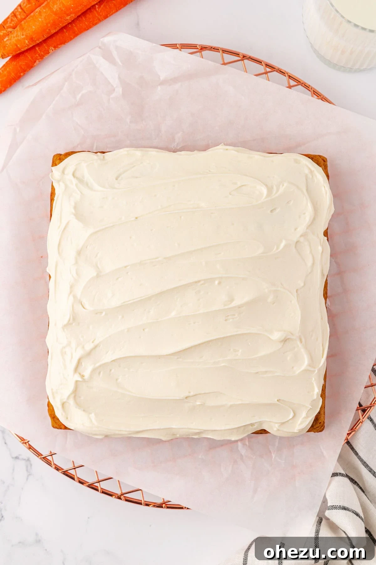 Fully frosted carrot cake in the pan, with a thick layer of white cream cheese frosting.